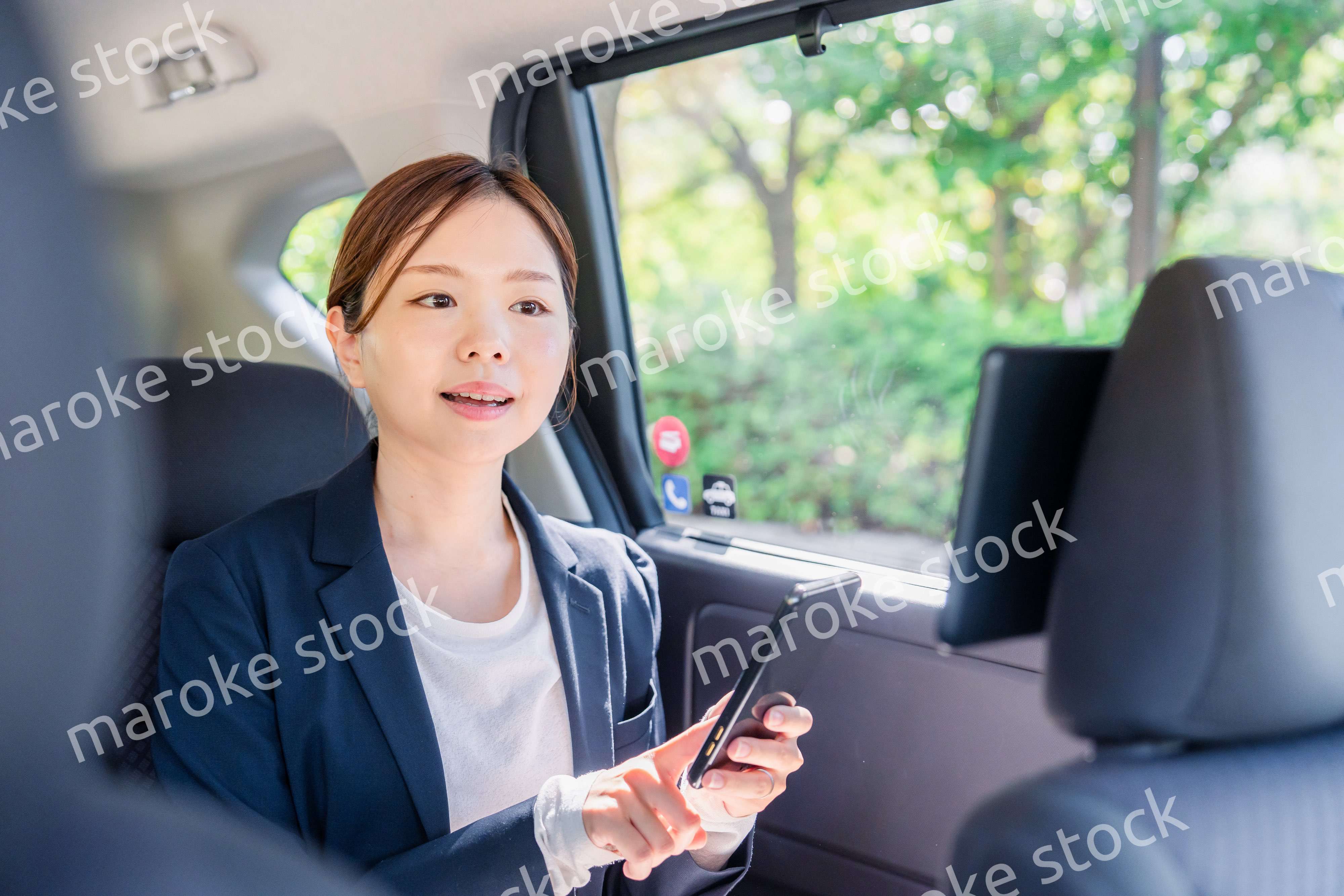 タクシーでスマホを使う若い女性ビジネスパーソン