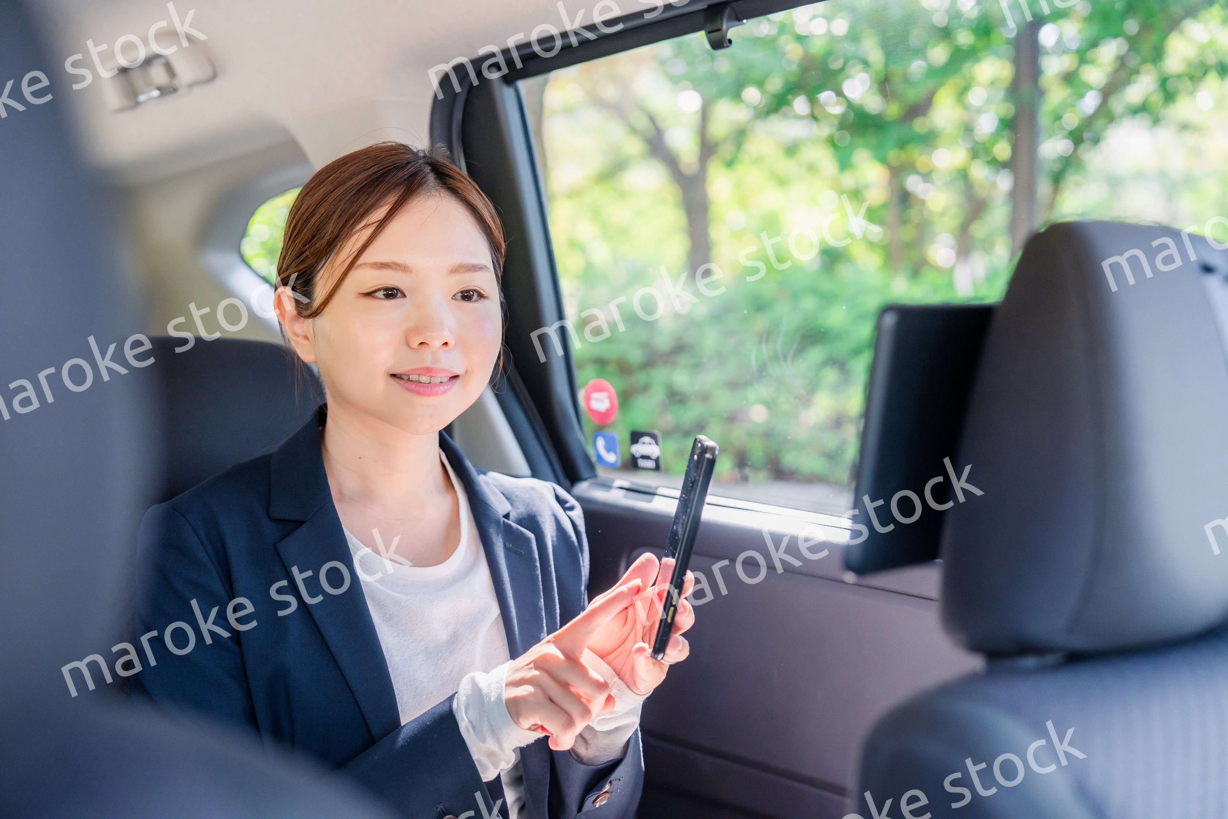 タクシーでスマホを使う若い女性ビジネスパーソン