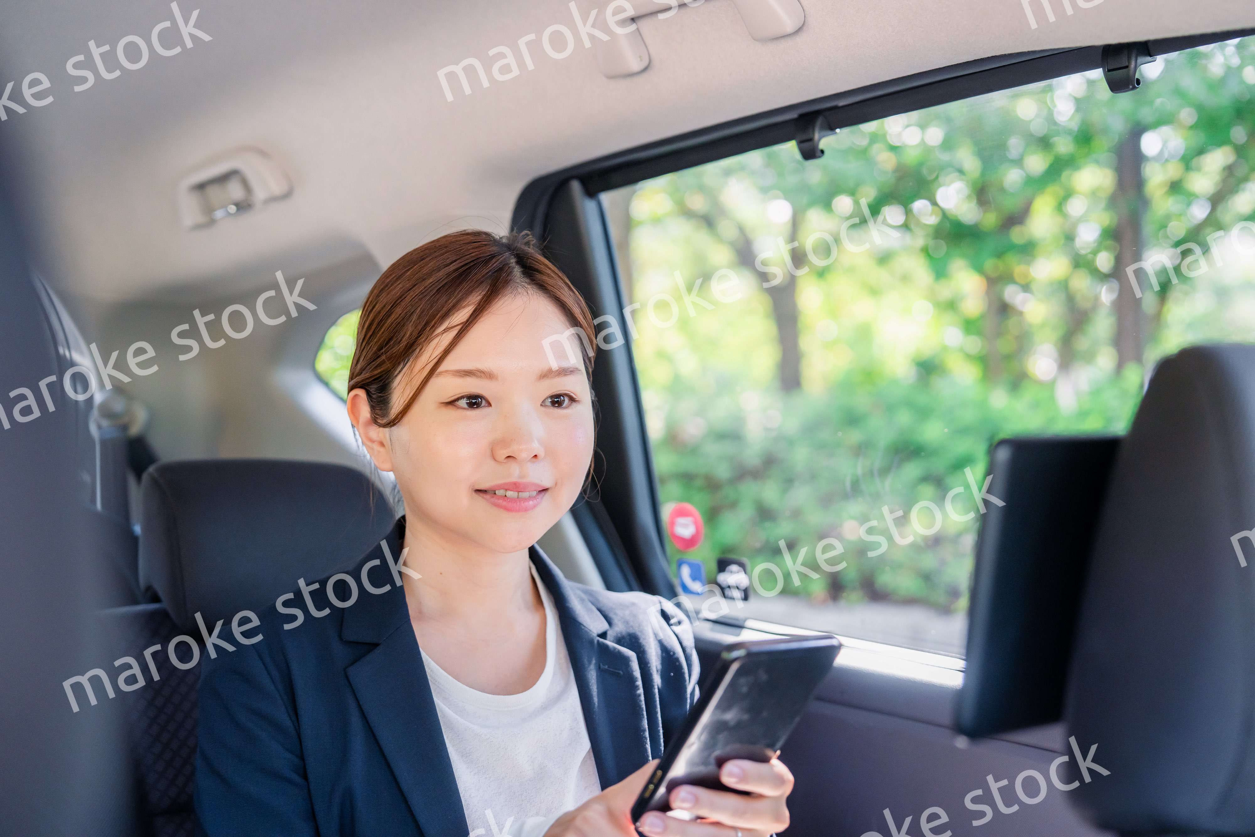 タクシーでスマホを使う若い女性ビジネスパーソン