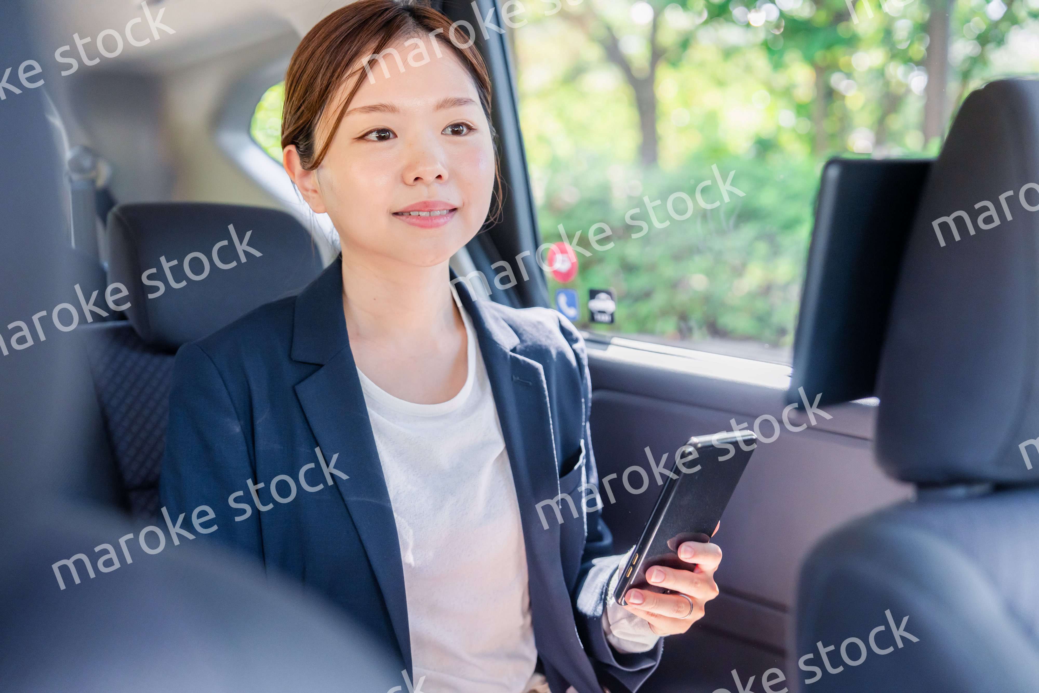 タクシーでスマホを使う若い女性ビジネスパーソン