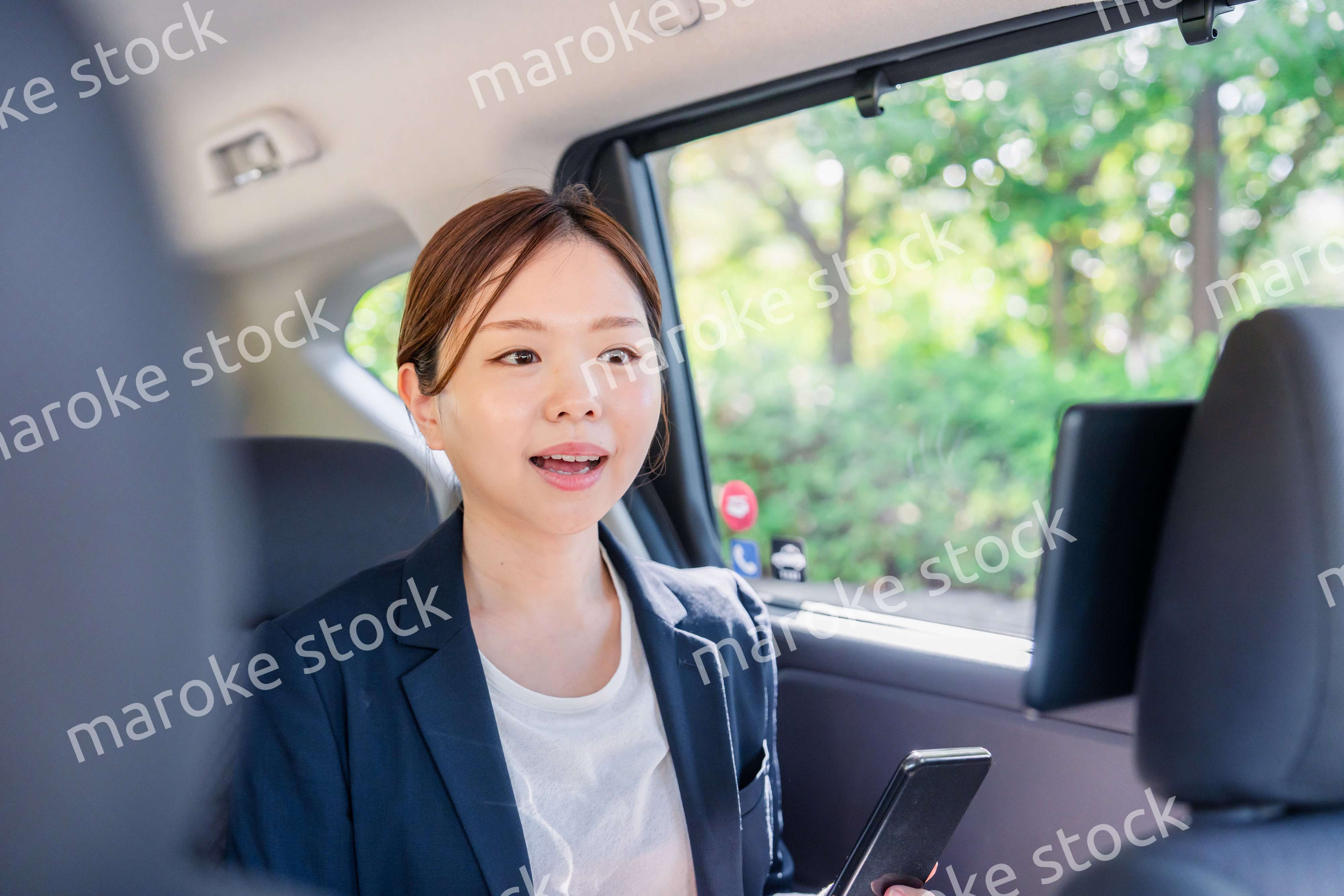 タクシーでスマホを使う若い女性ビジネスパーソン