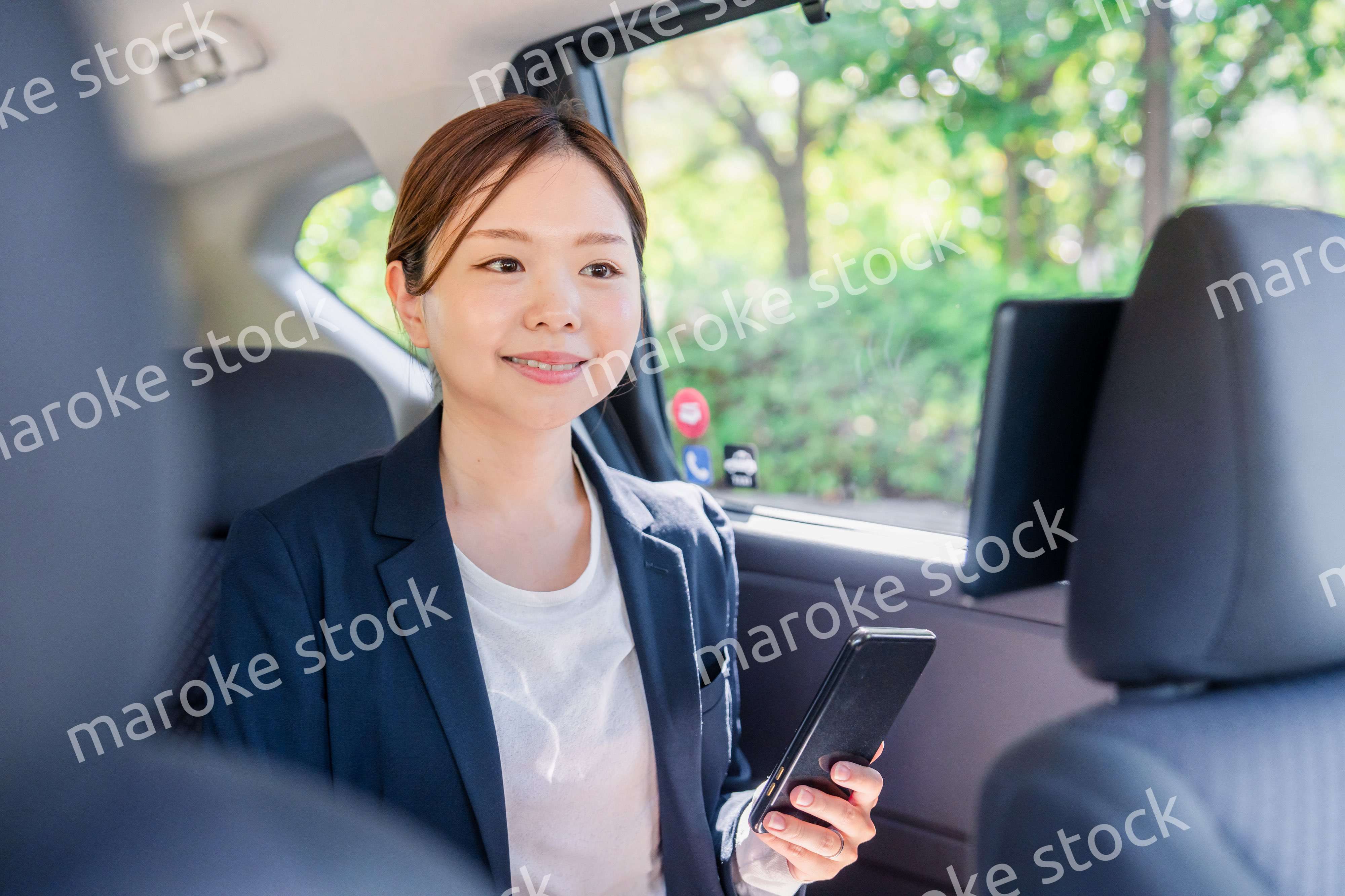 タクシーでスマホを使う若い女性ビジネスパーソン