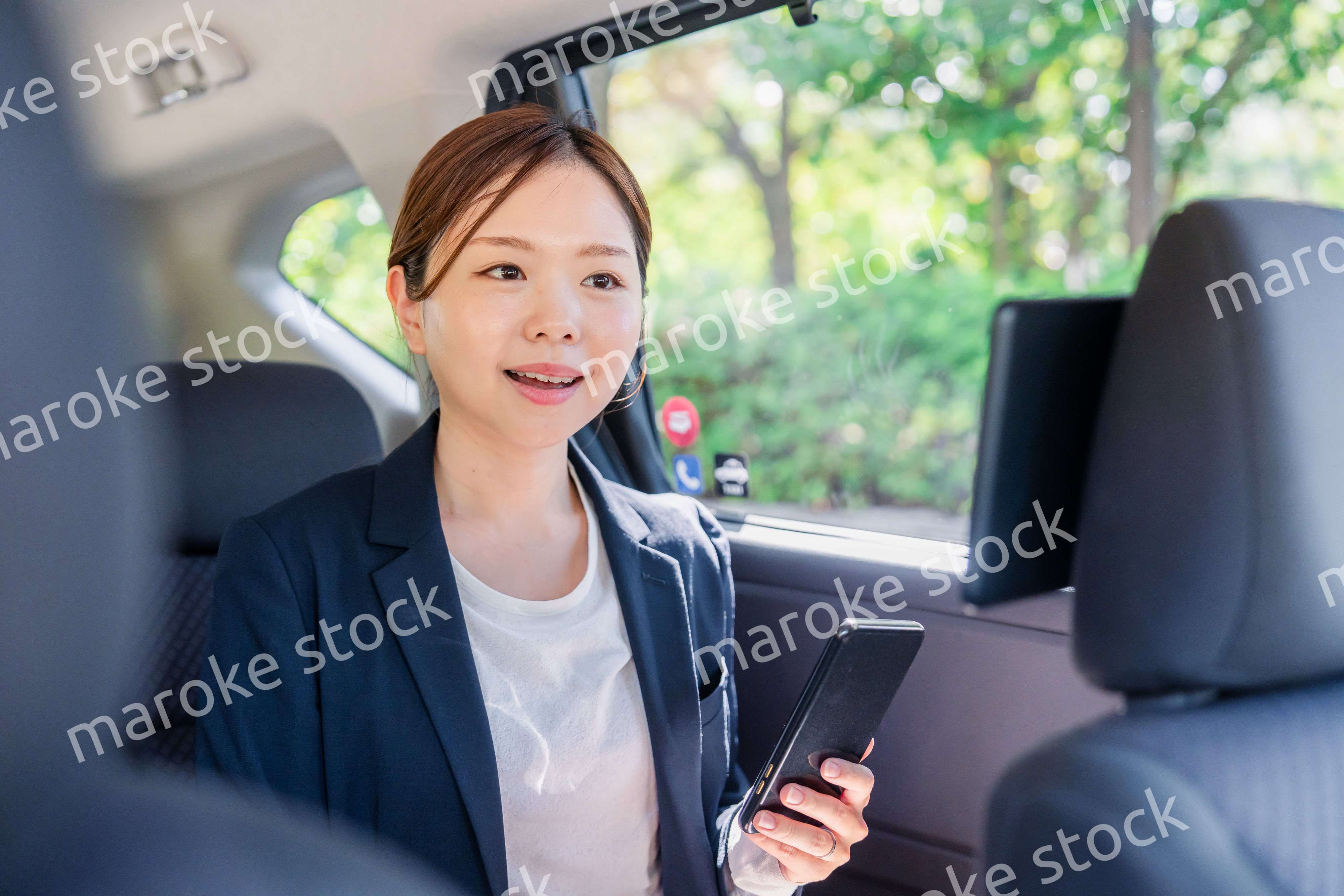 タクシーでスマホを使う若い女性ビジネスパーソン