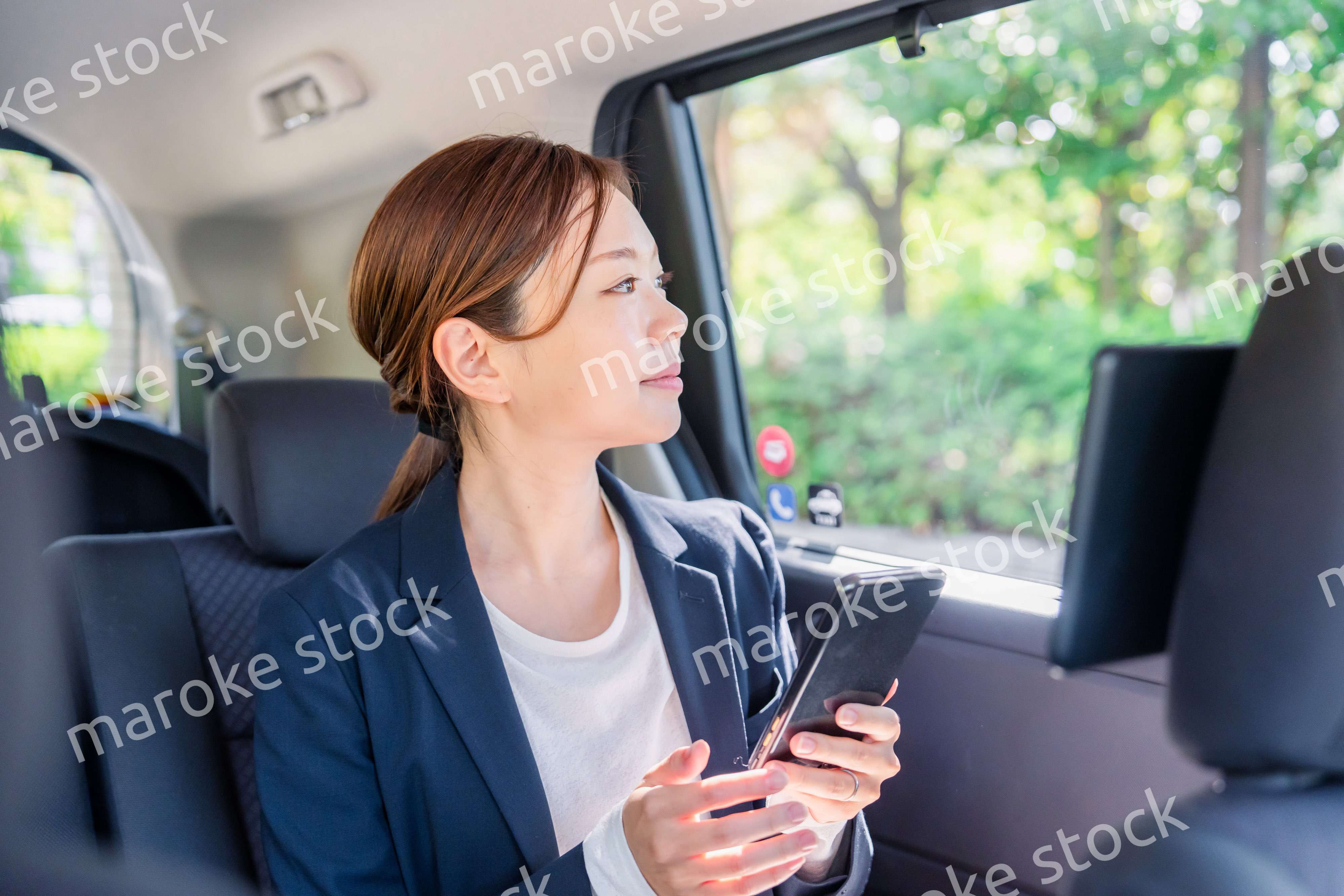 タクシーでスマホを使う若い女性ビジネスパーソン