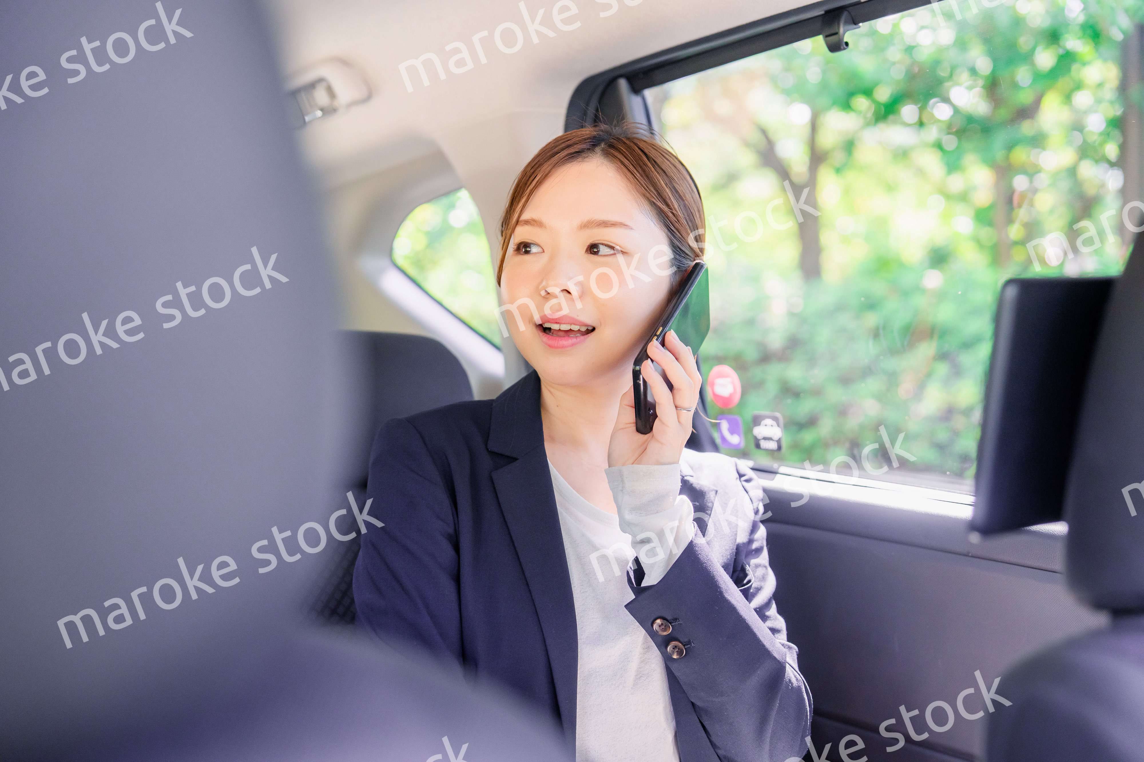 タクシーに乗って電話をする若い営業の女性