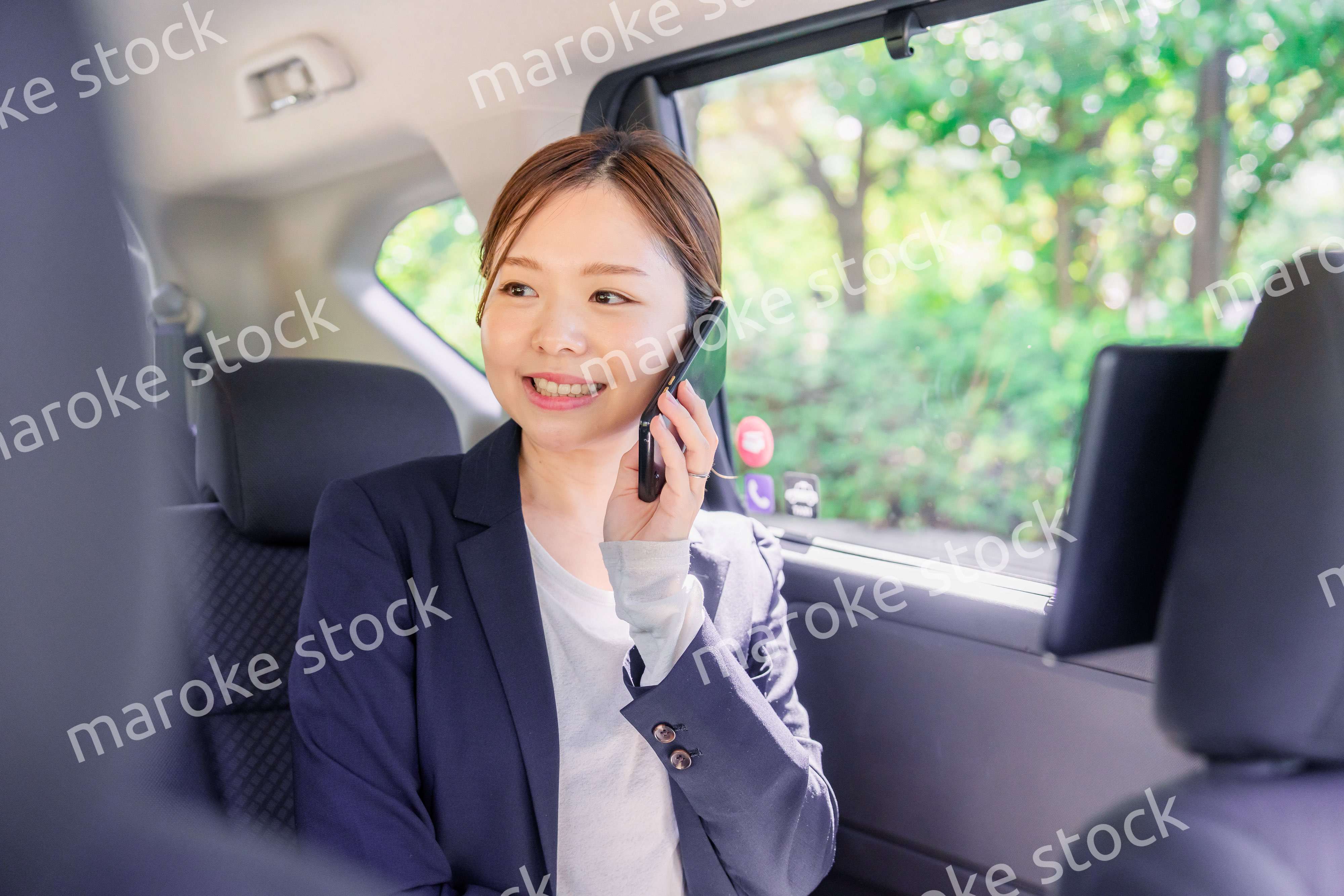 タクシーに乗って電話をする若い営業の女性