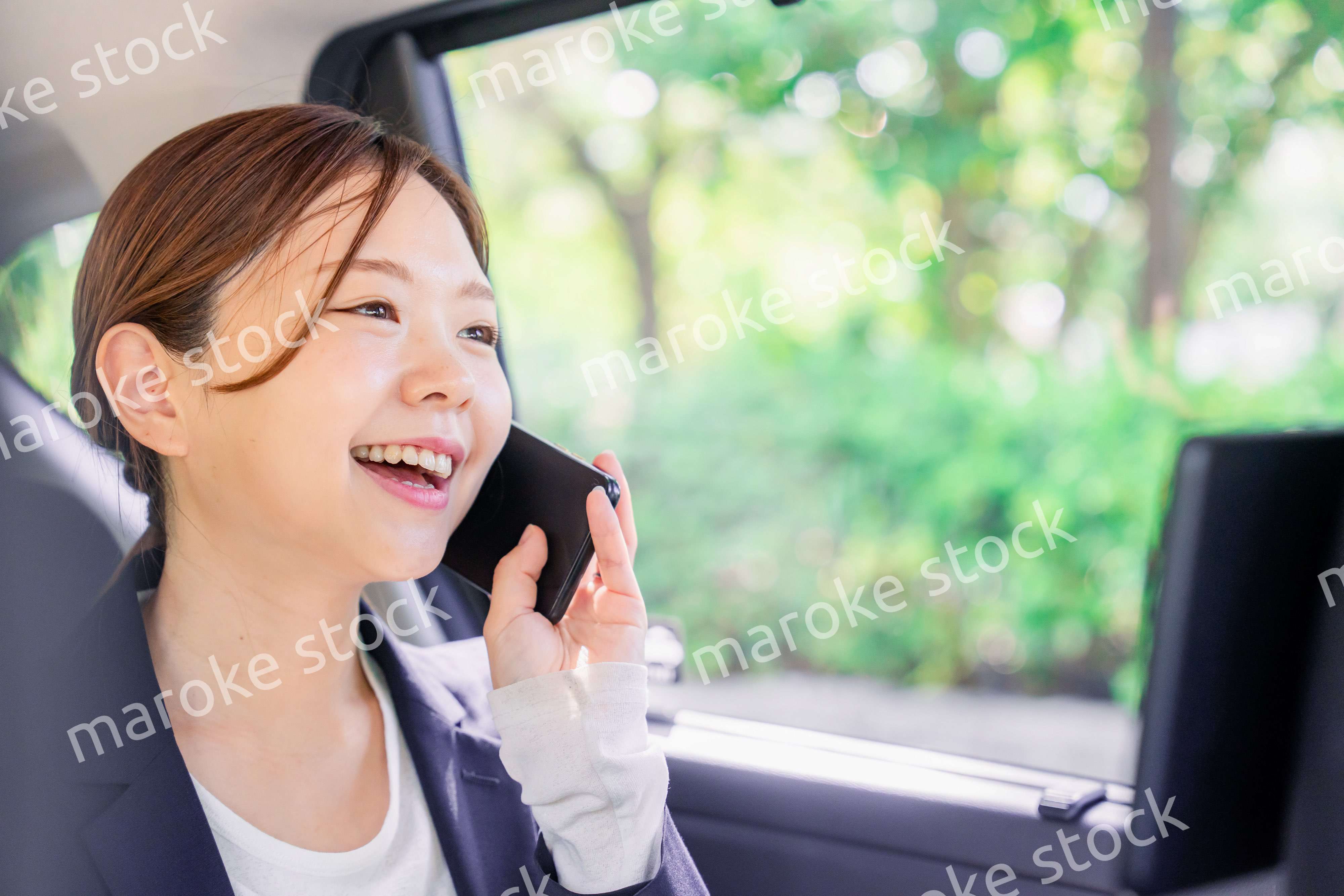 タクシーに乗って電話をする若い営業の女性