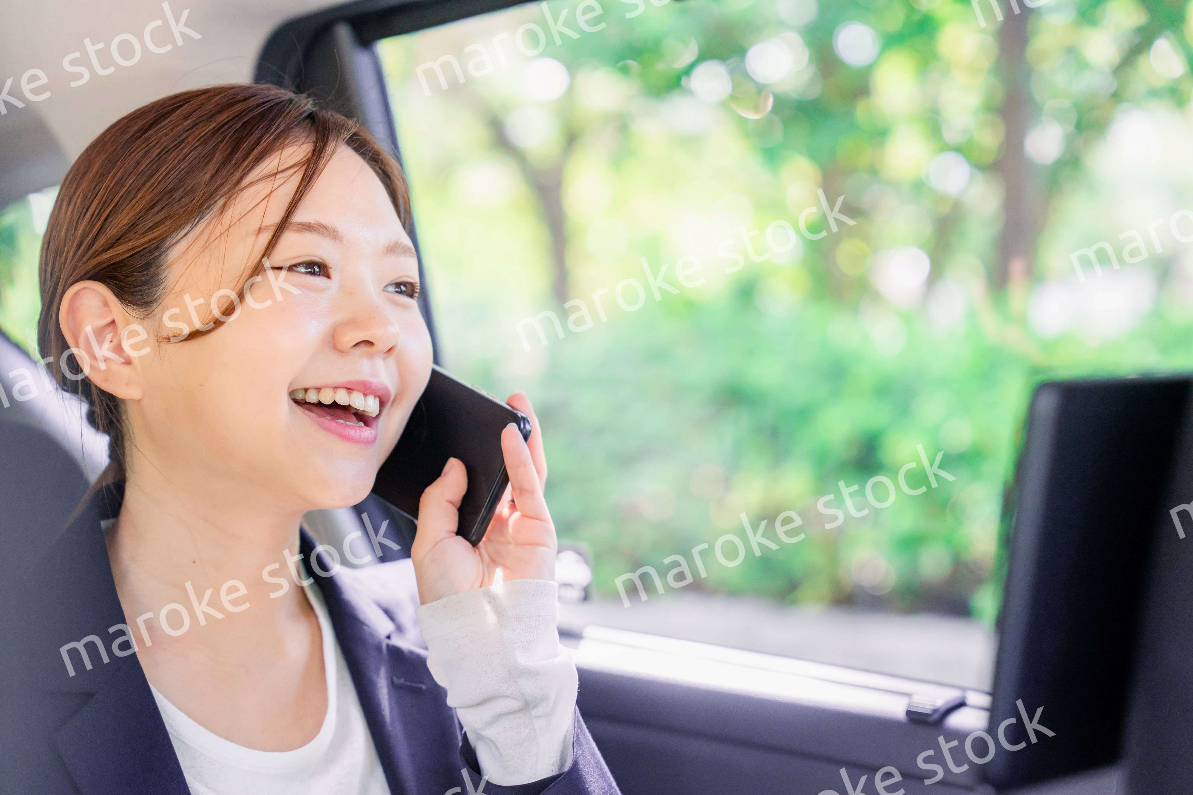 タクシーに乗って電話をする若い営業の女性