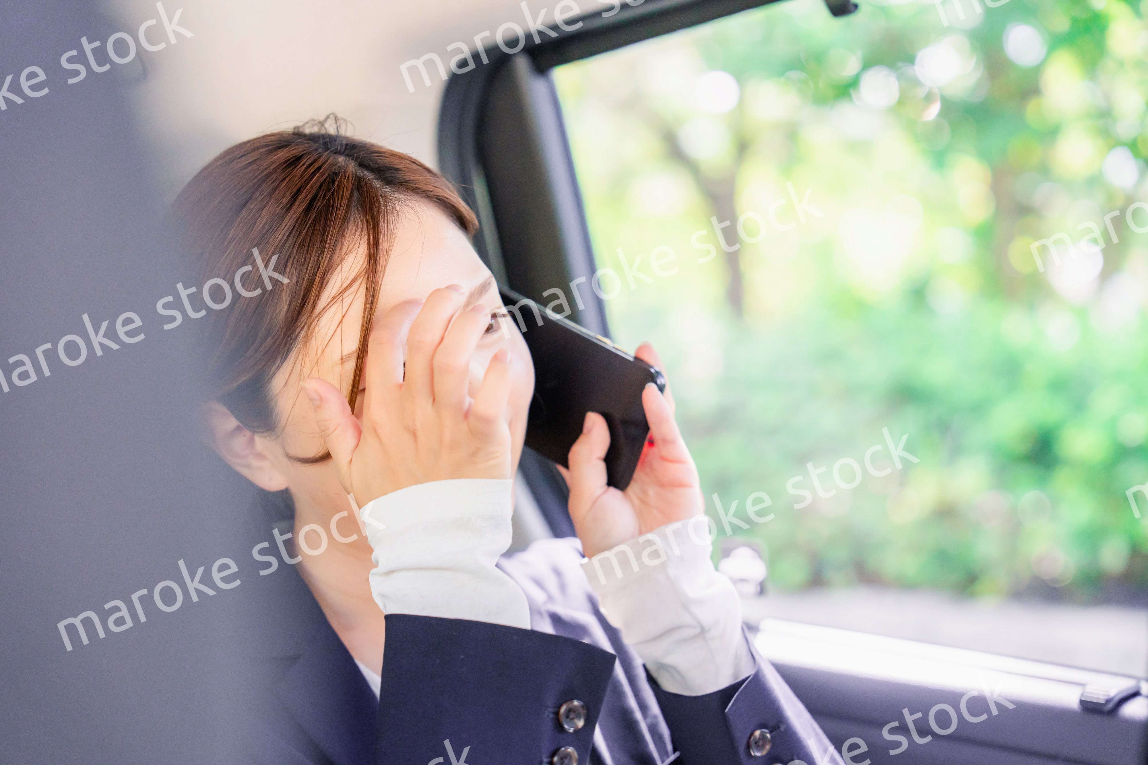 タクシーに乗って電話をする若い営業の女性