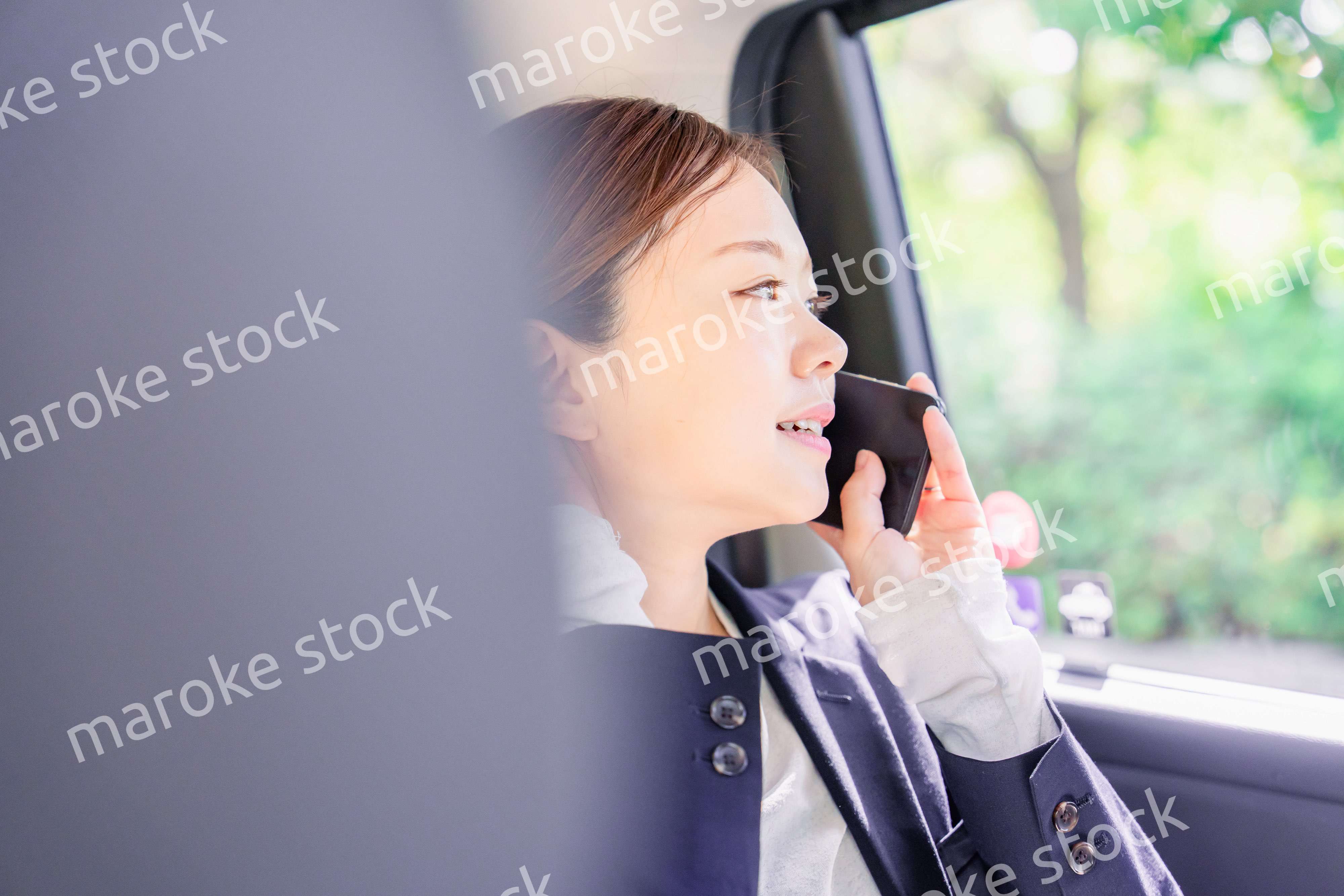 タクシーに乗って電話をする若い営業の女性