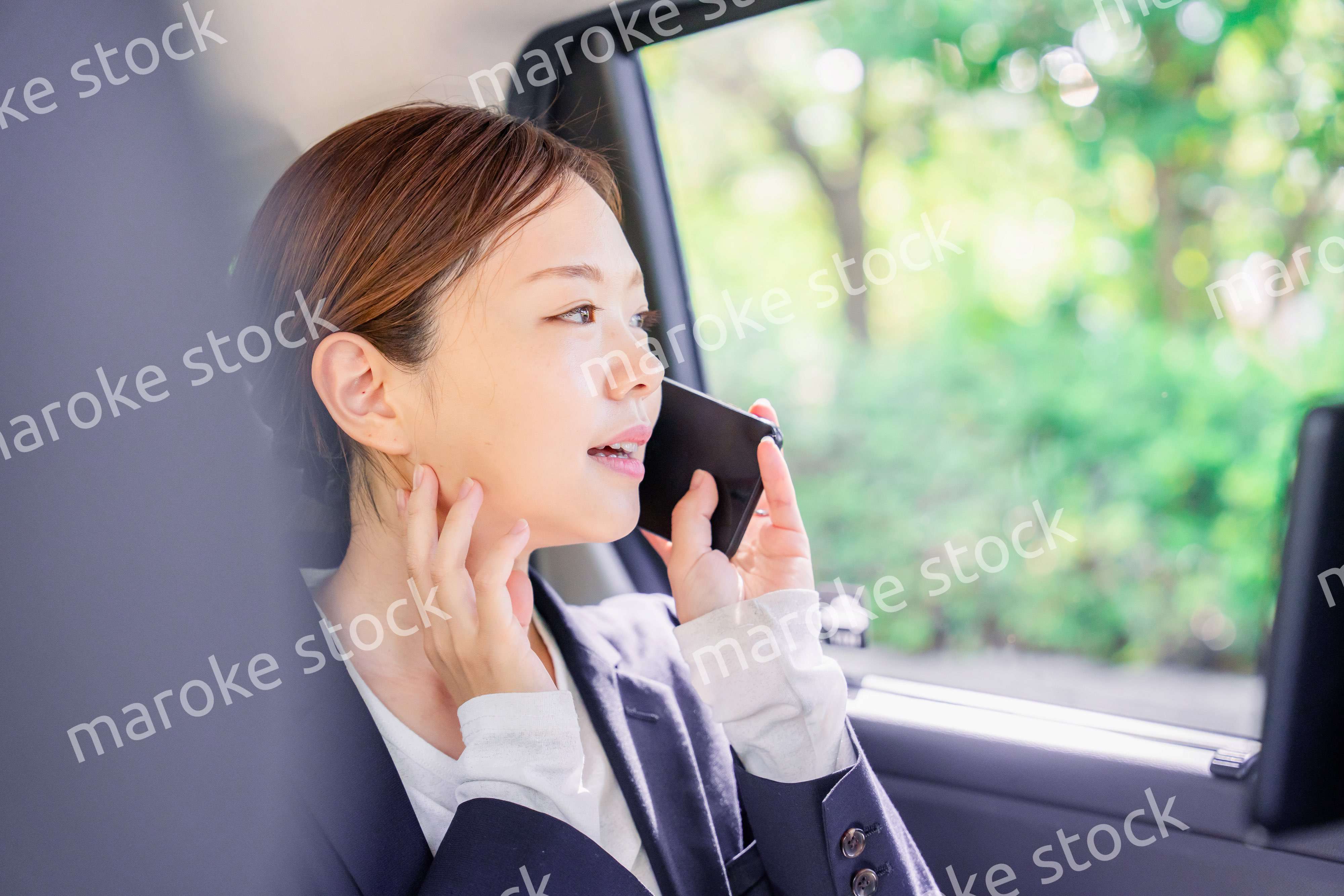 タクシーに乗って電話をする若い営業の女性