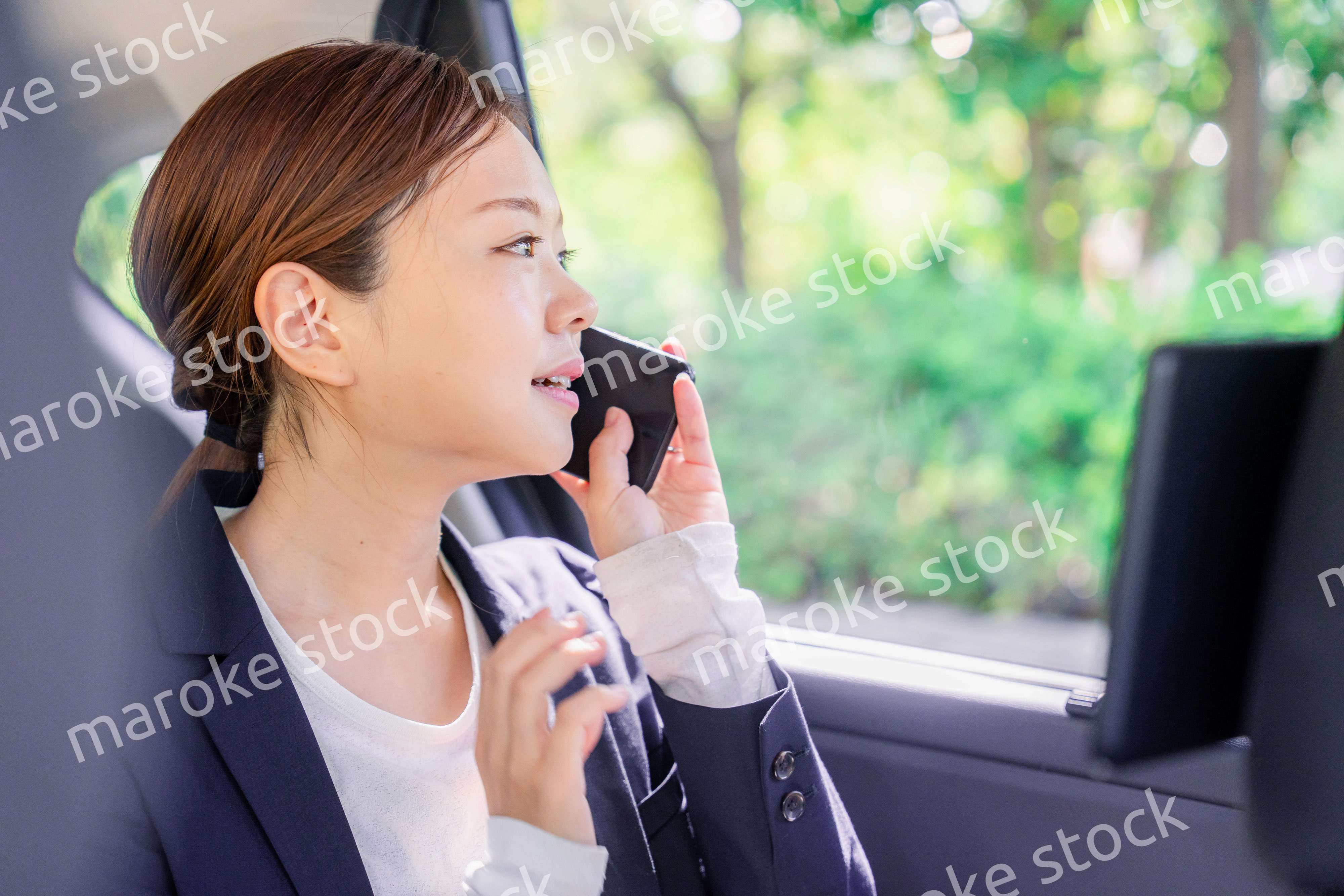 タクシーに乗って電話をする若い営業の女性