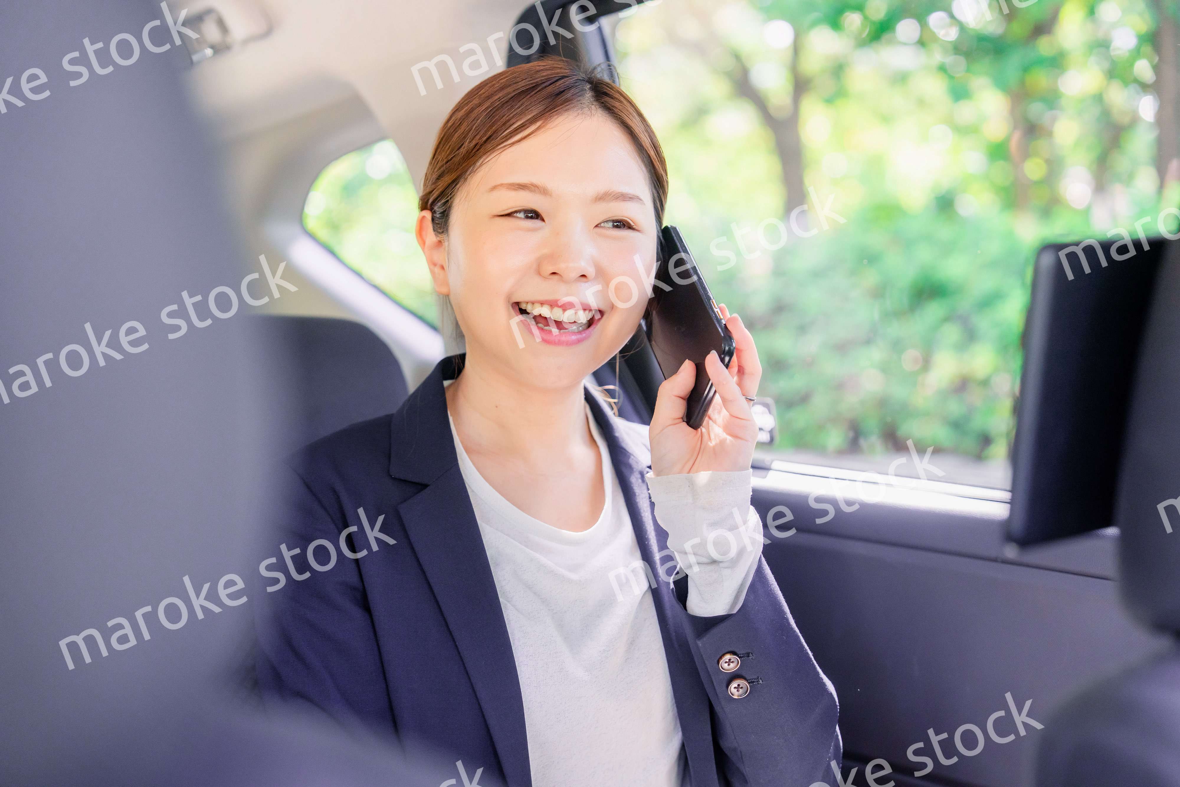 タクシーに乗って電話をする若い営業の女性