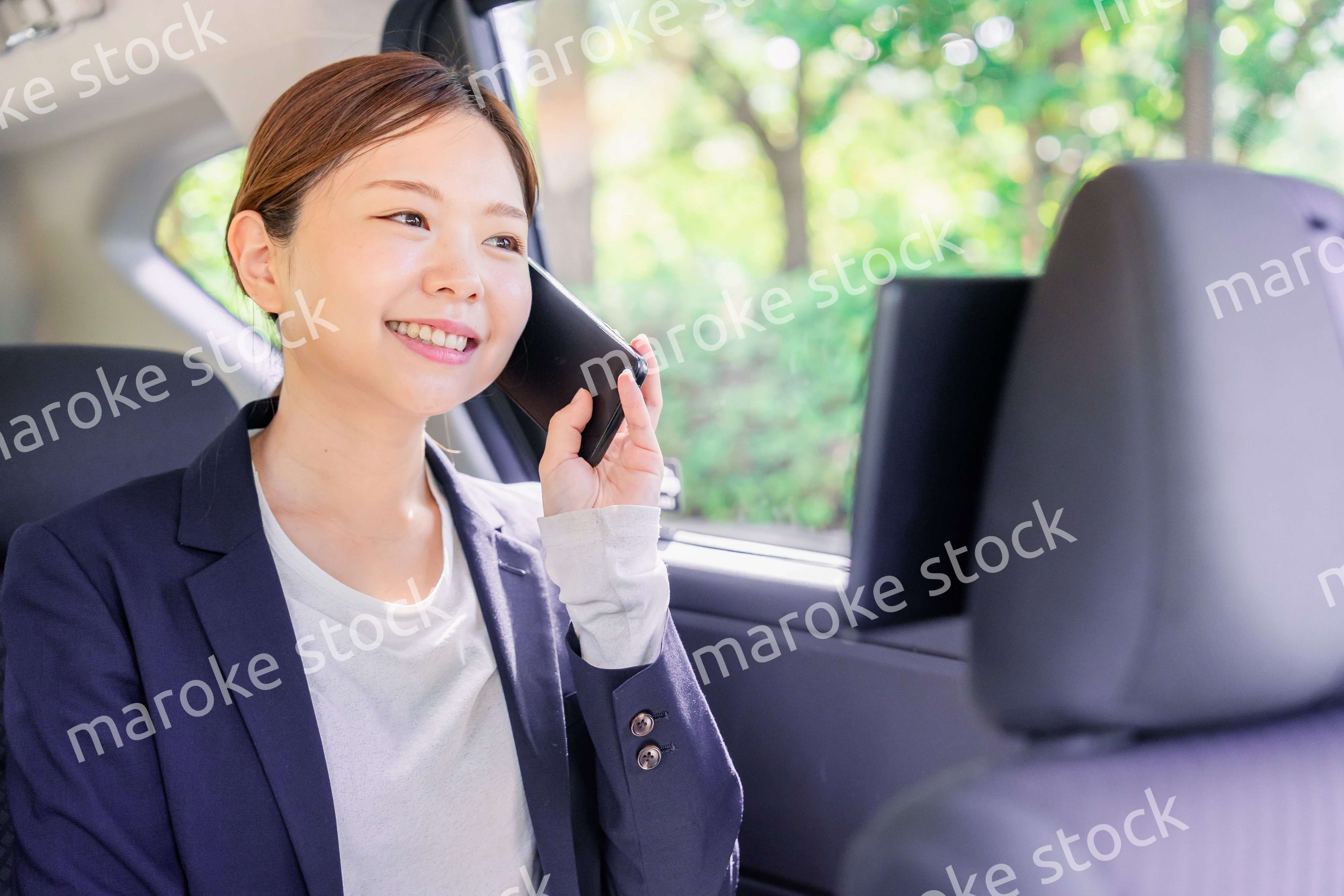 タクシーに乗って電話をする若い営業の女性