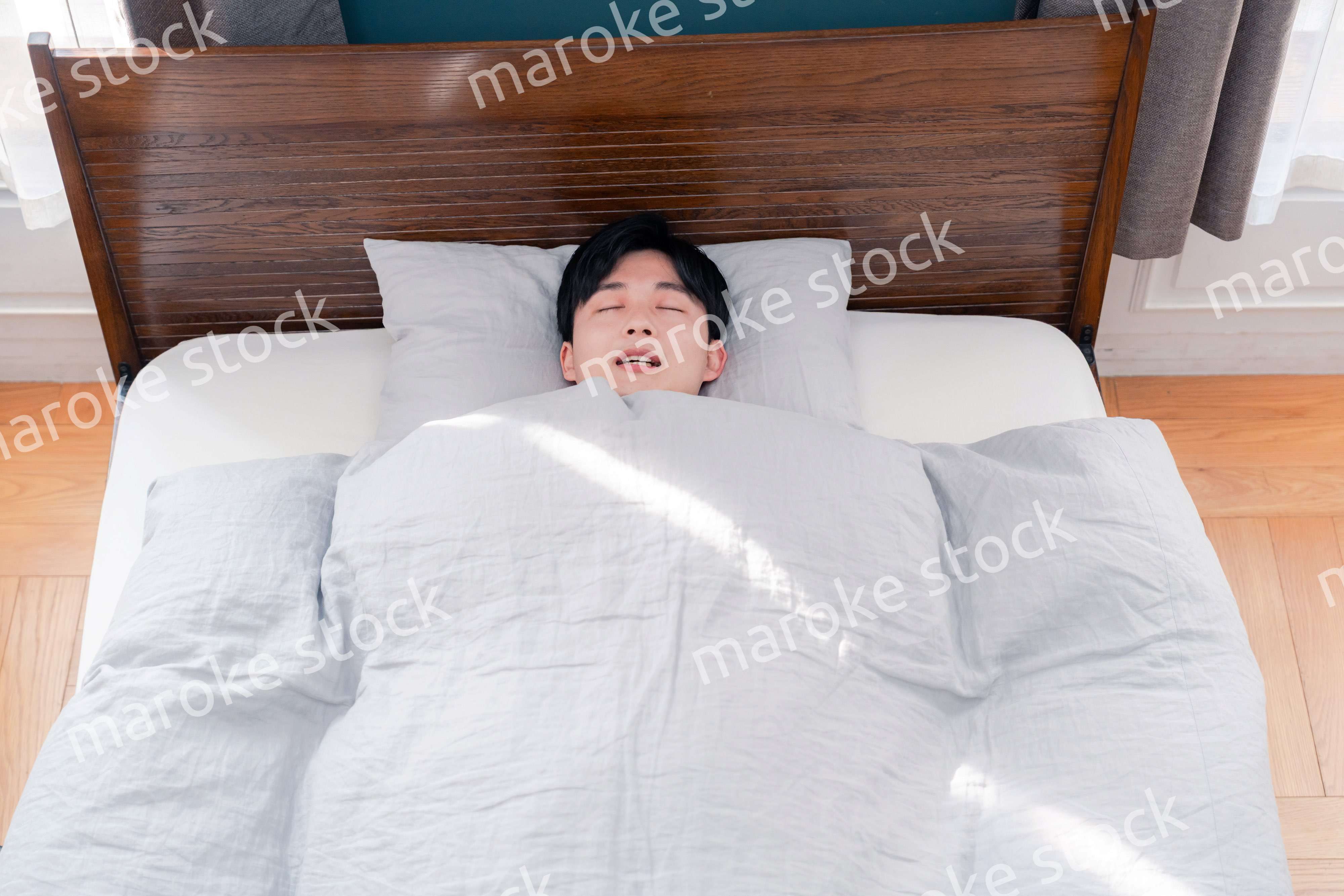 朝日が差し込む中で寝る若い男性