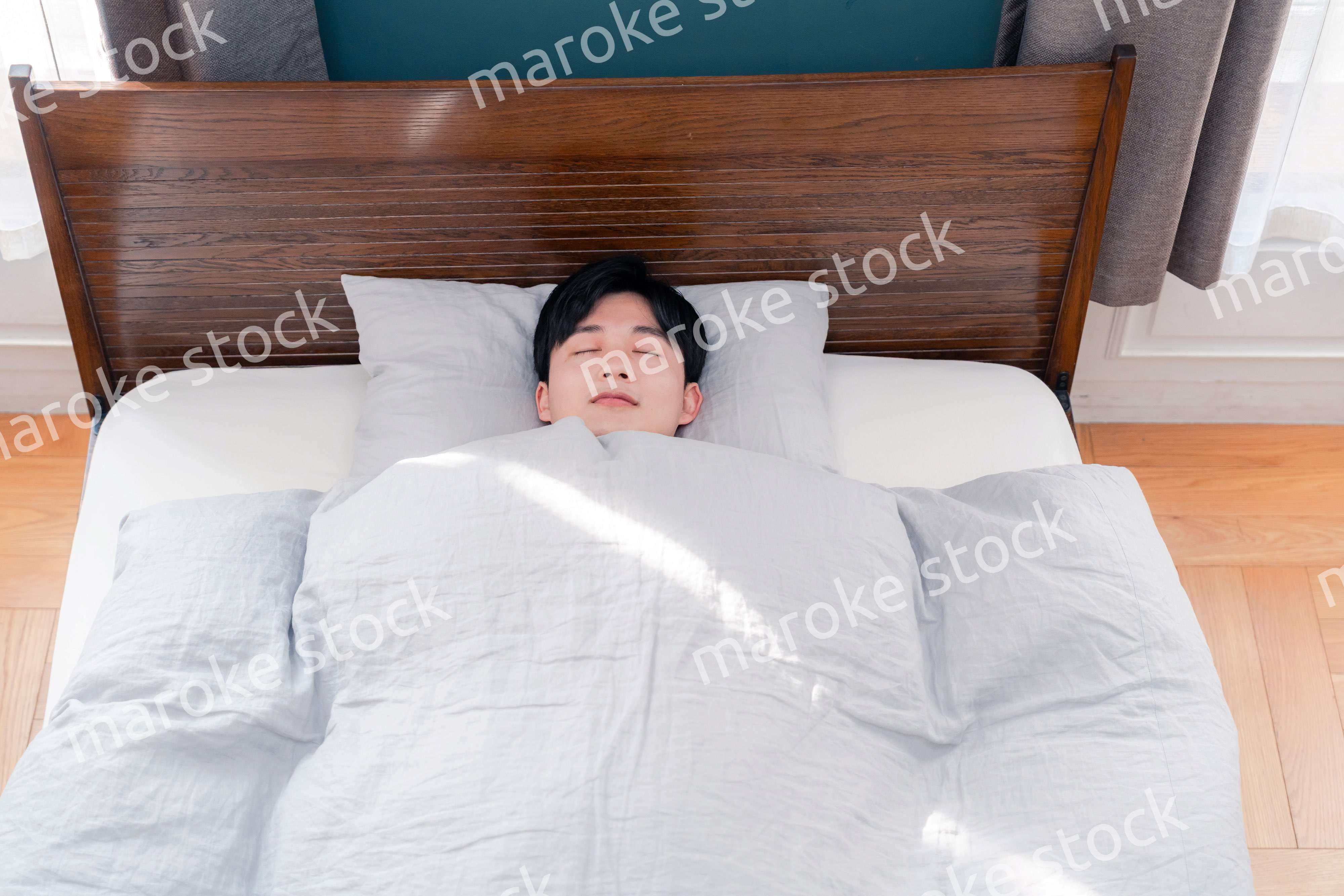 朝日が差し込む中で寝る若い男性