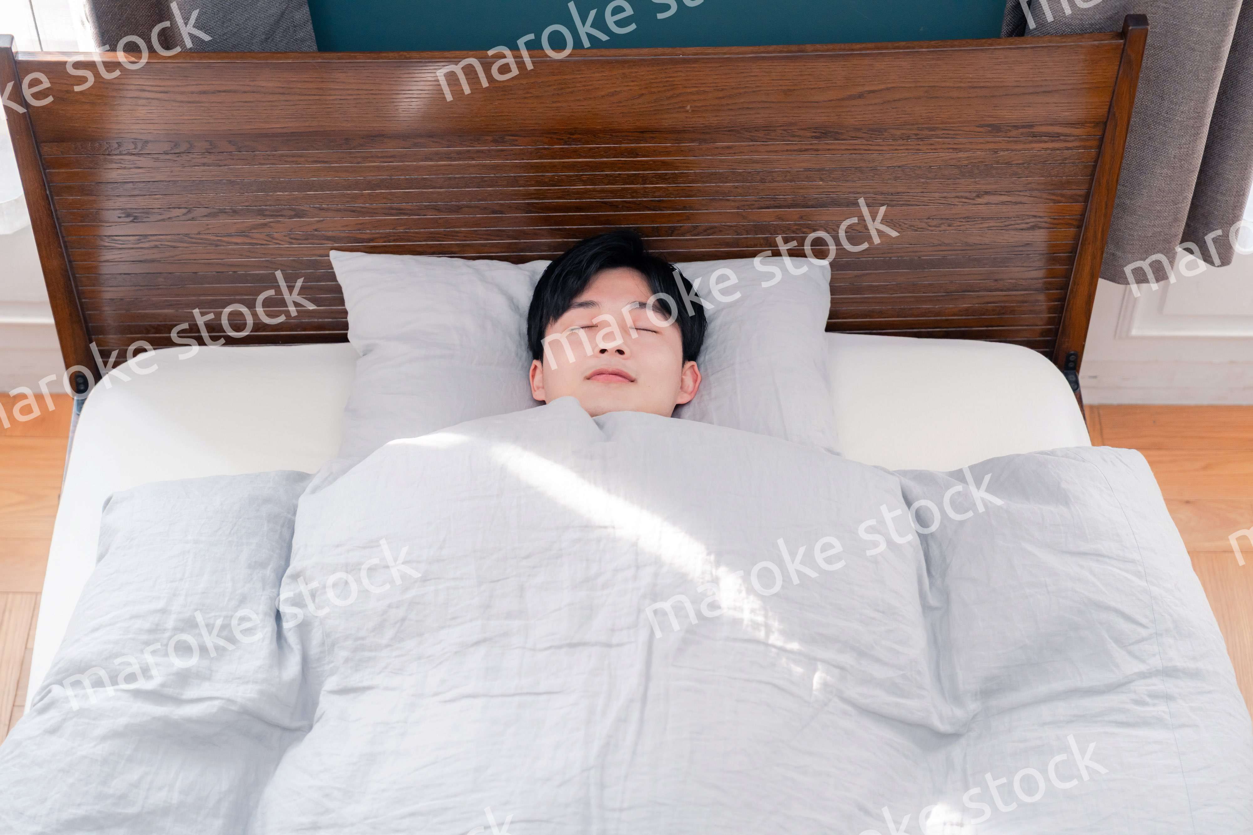 朝日が差し込む中で寝る若い男性