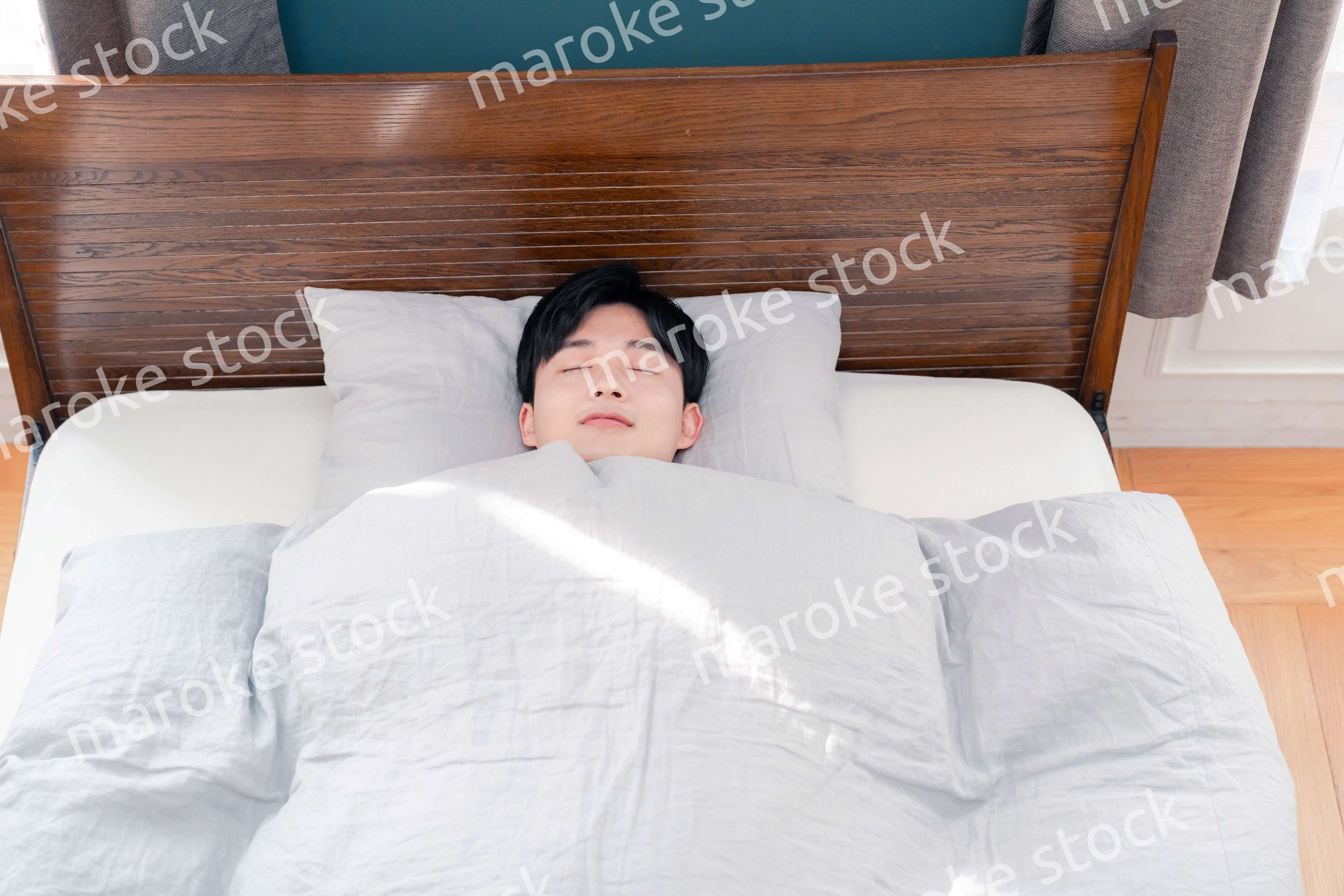 朝日が差し込む中で寝る若い男性