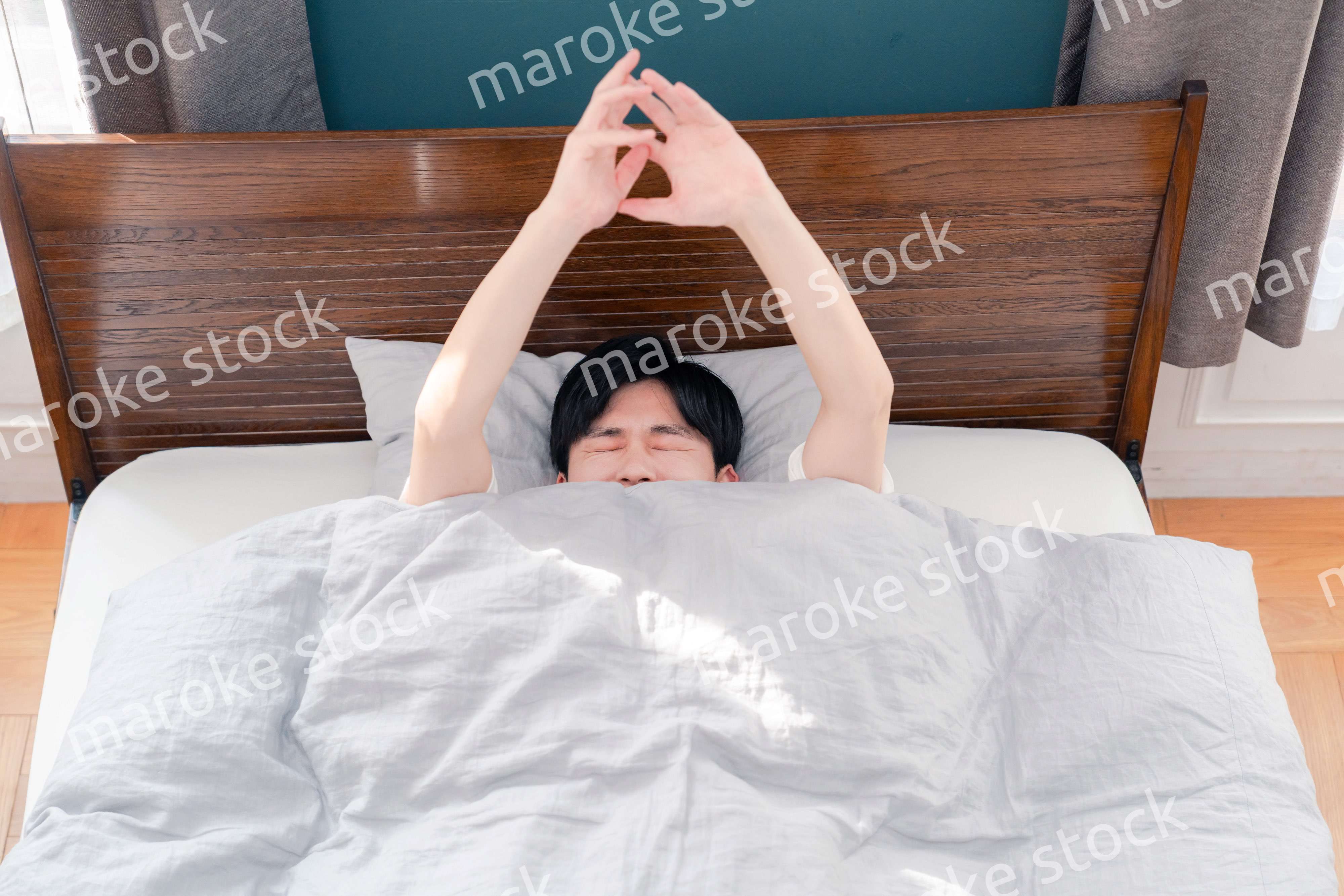 朝日が差し込む中で爽やかに目覚める若い男性