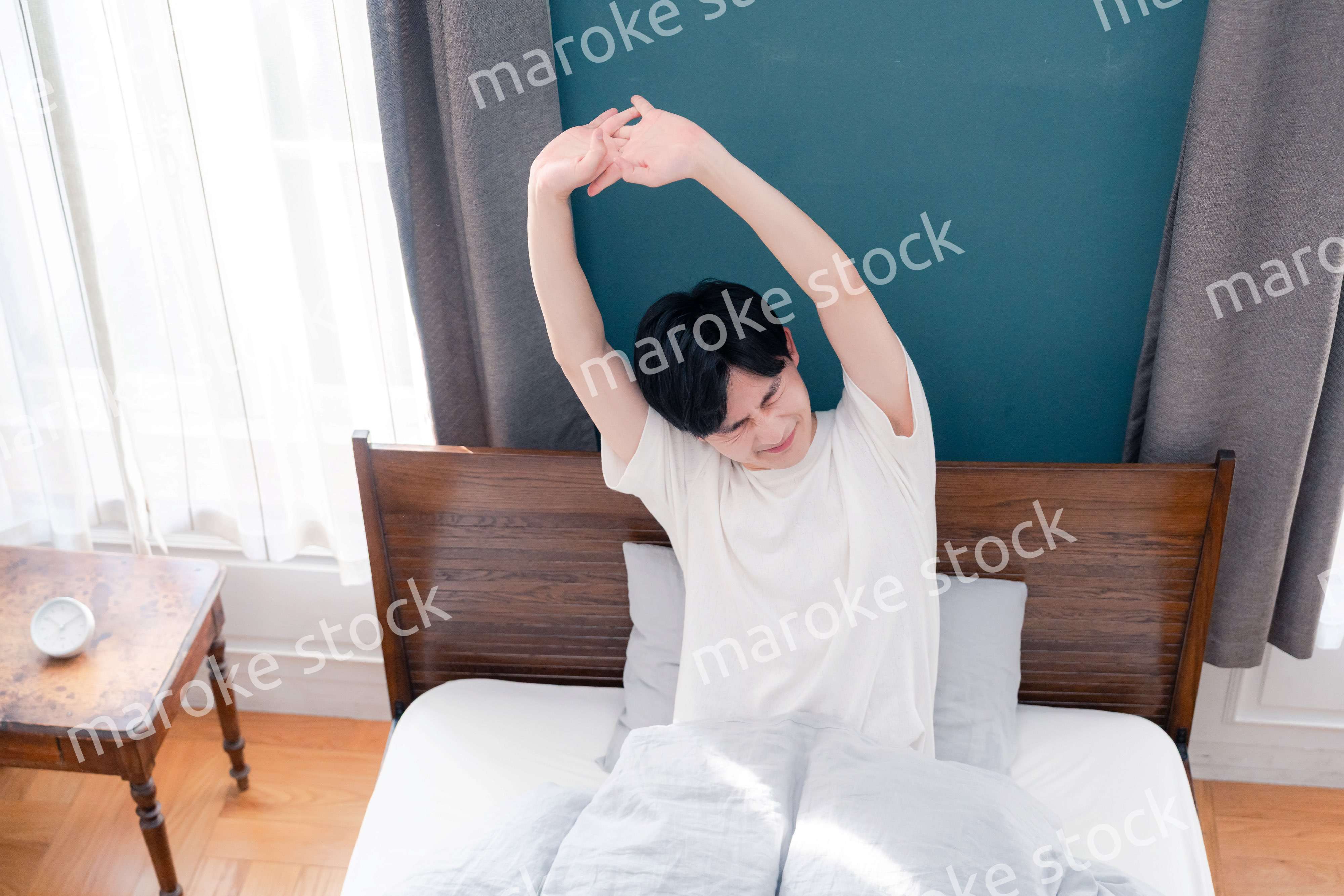 朝日が差し込む中で爽やかに目覚める若い男性