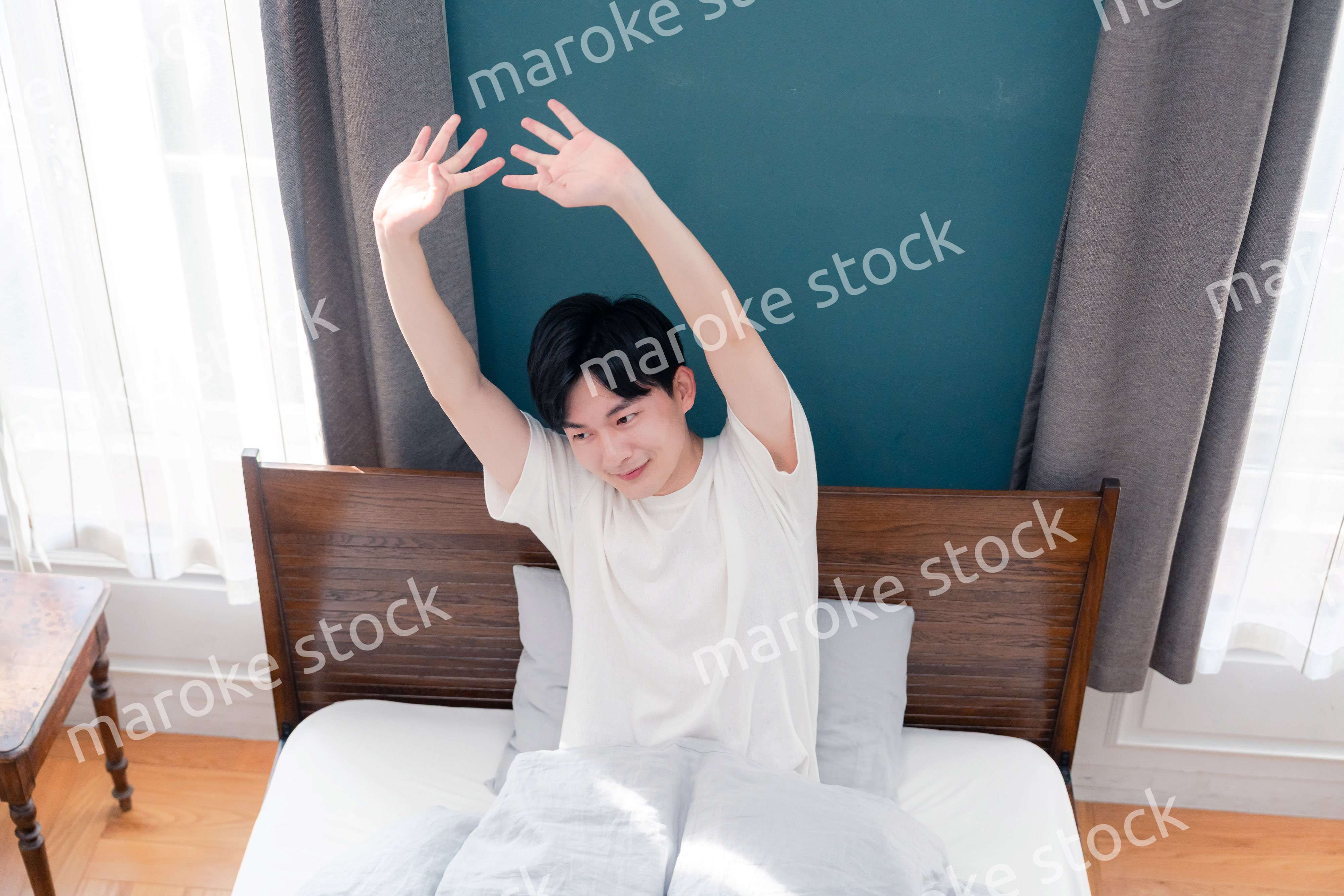 朝日が差し込む中で爽やかに目覚める若い男性