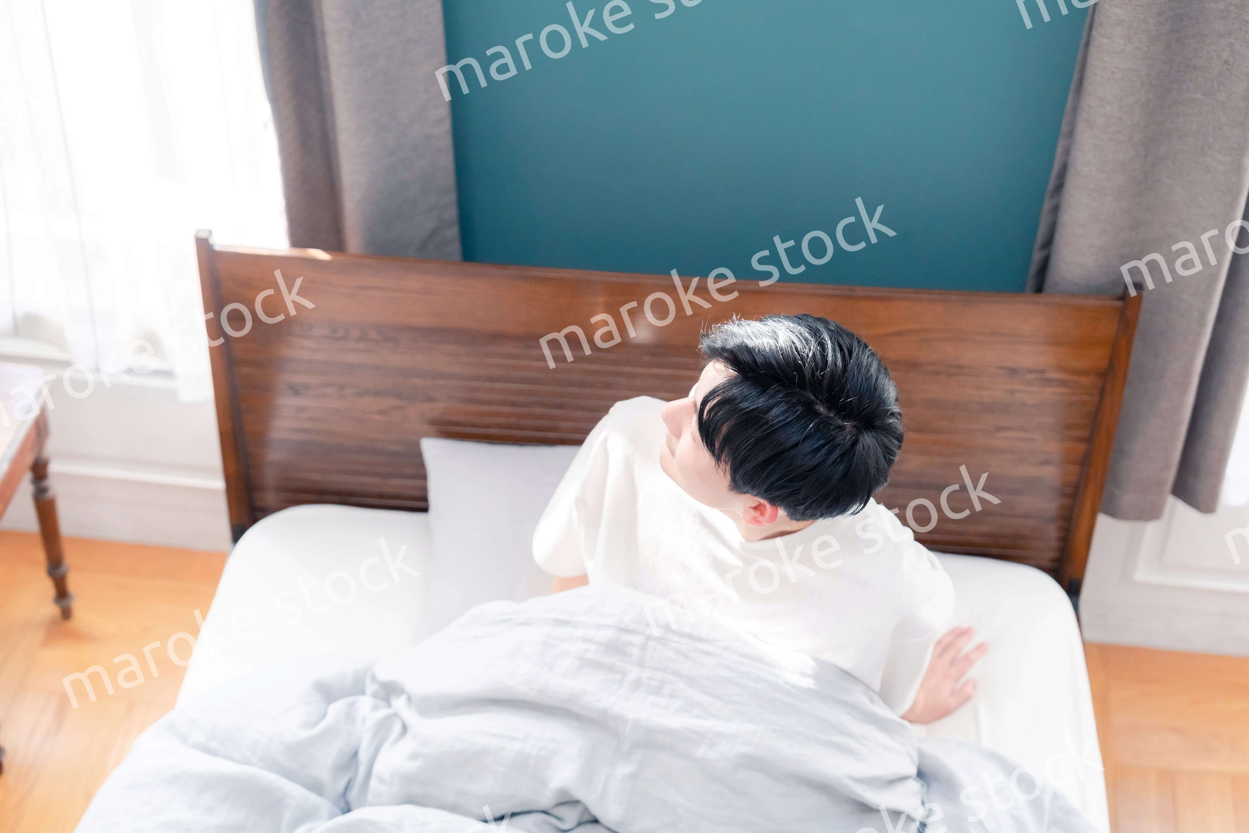 朝日が差し込む中で爽やかに目覚める若い男性