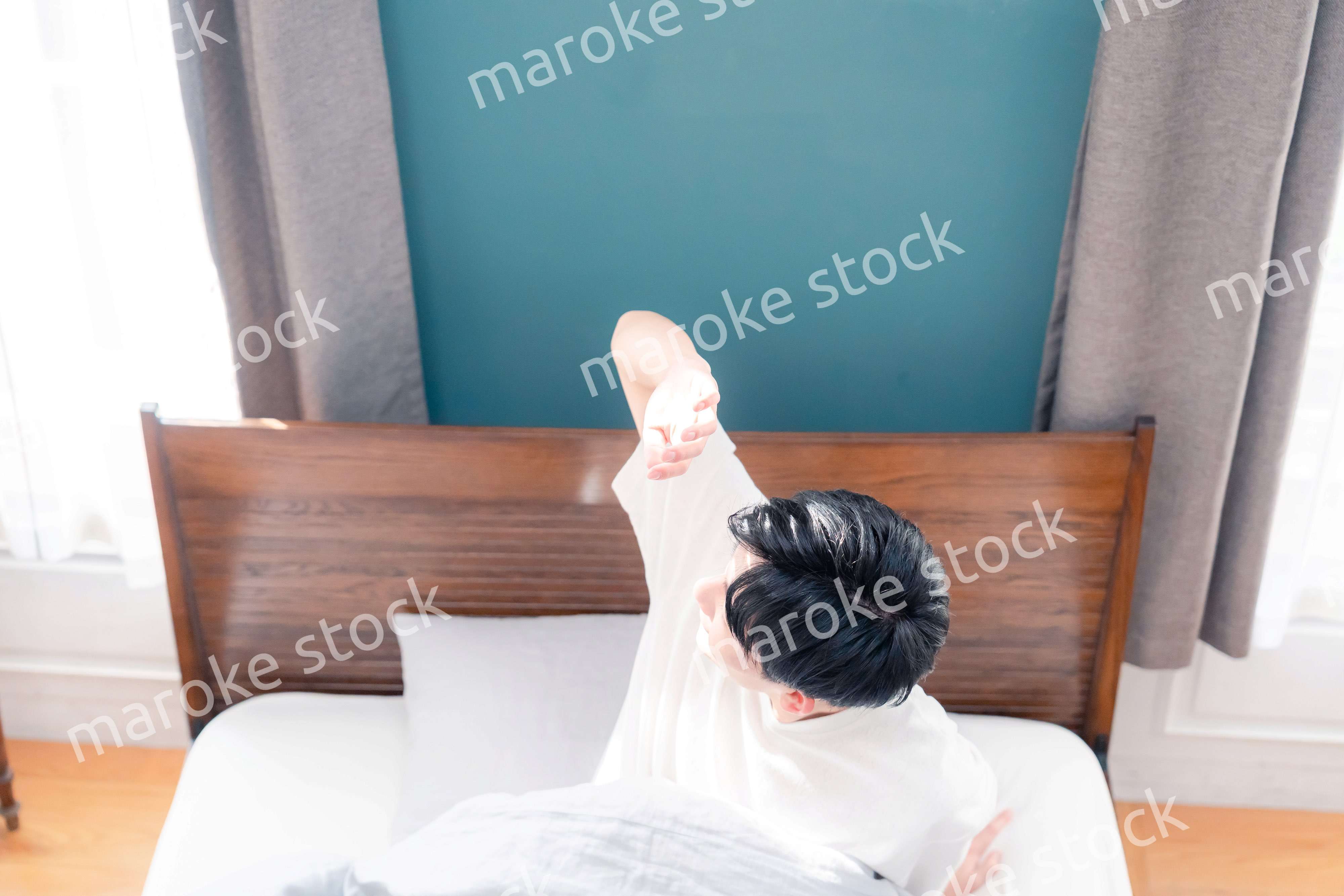 朝日が差し込む中で爽やかに目覚める若い男性