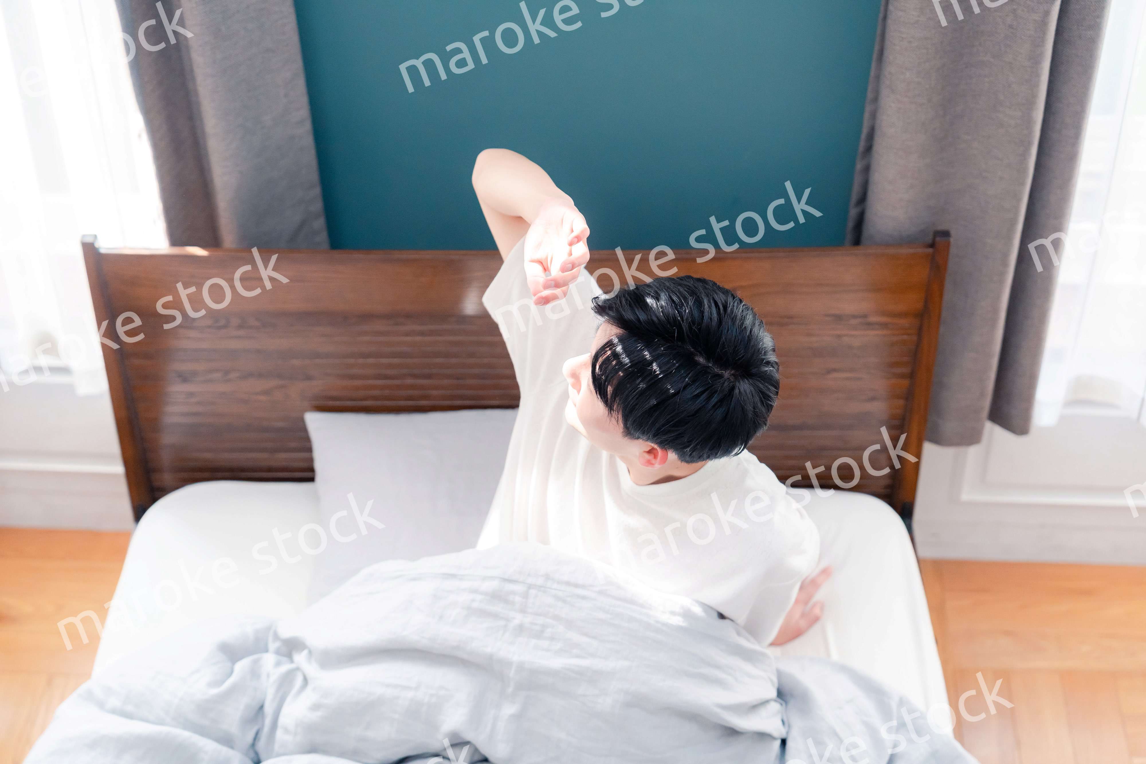 朝日が差し込む中で爽やかに目覚める若い男性