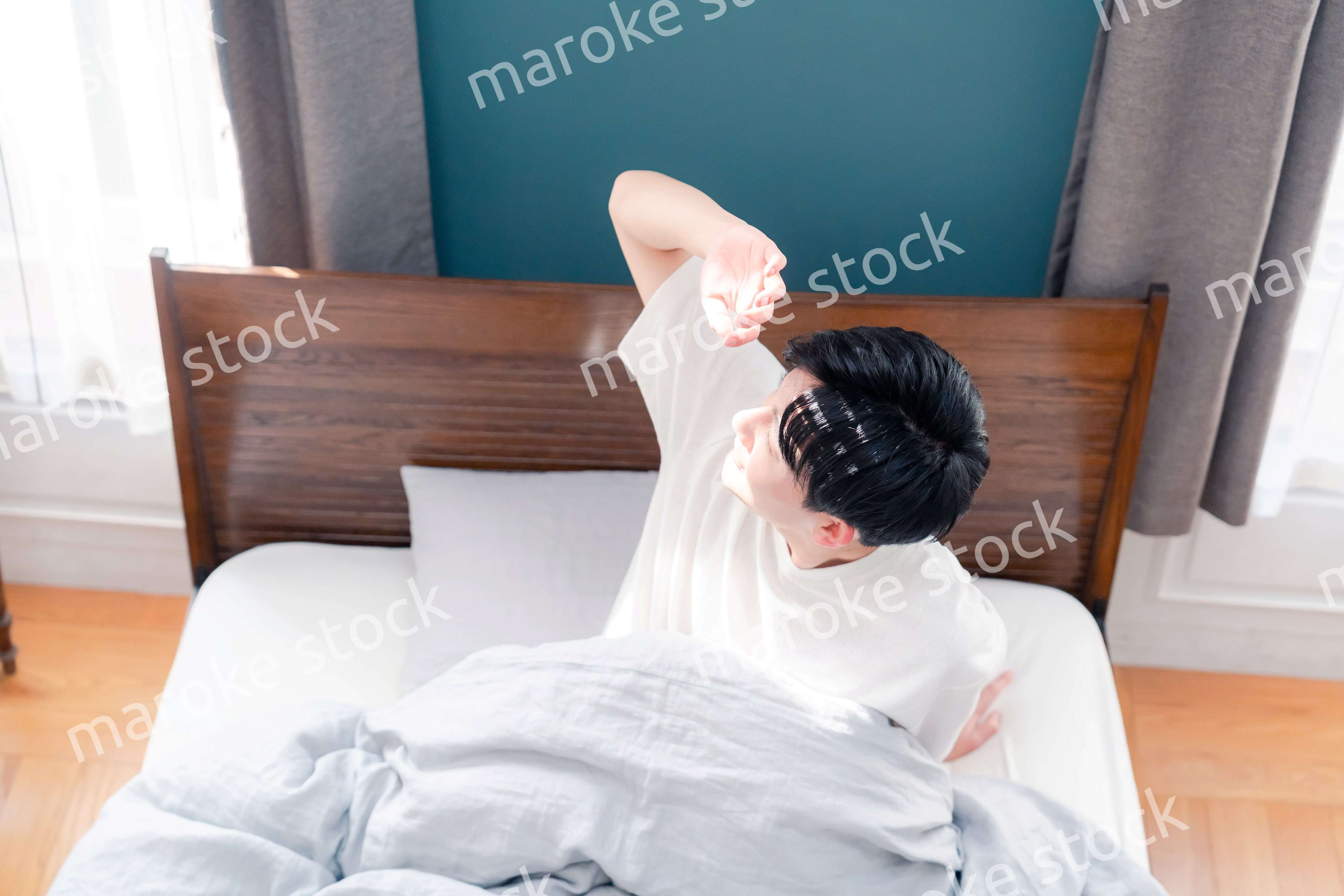 朝日が差し込む中で爽やかに目覚める若い男性