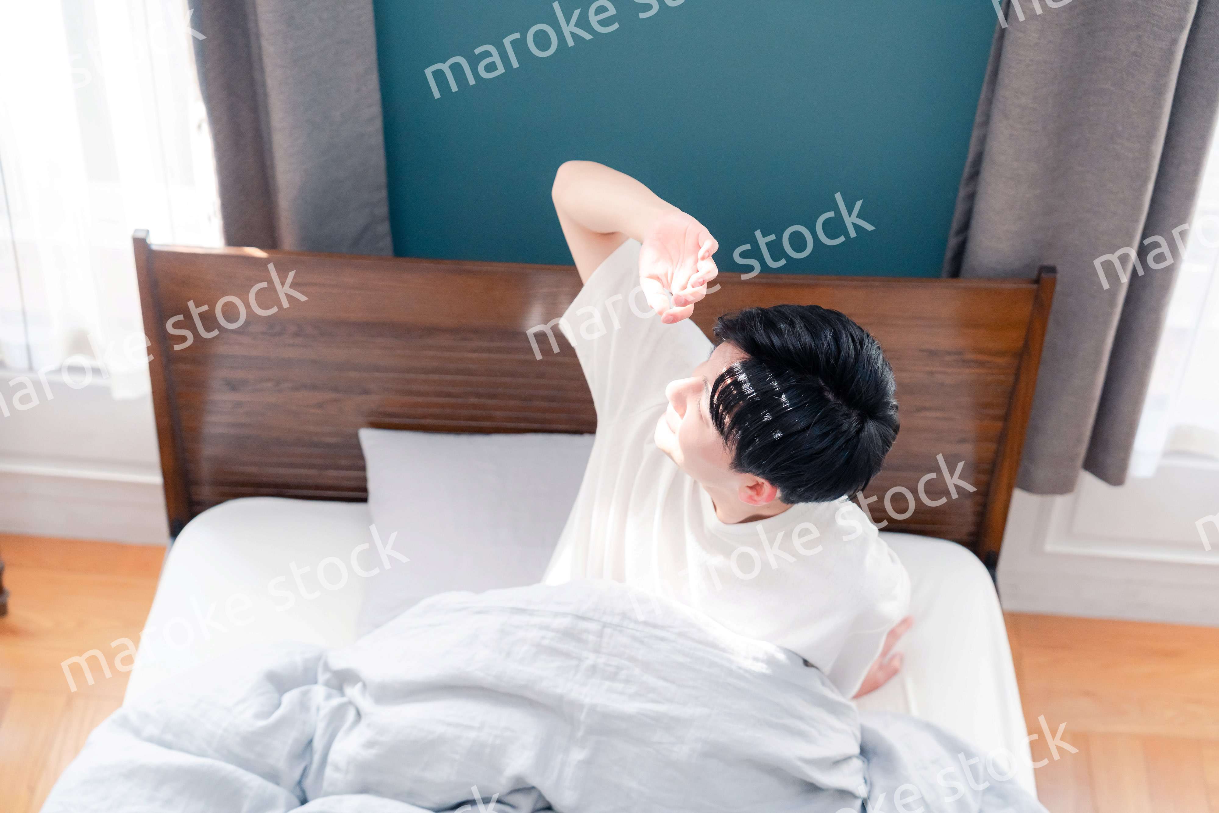 朝日が差し込む中で爽やかに目覚める若い男性