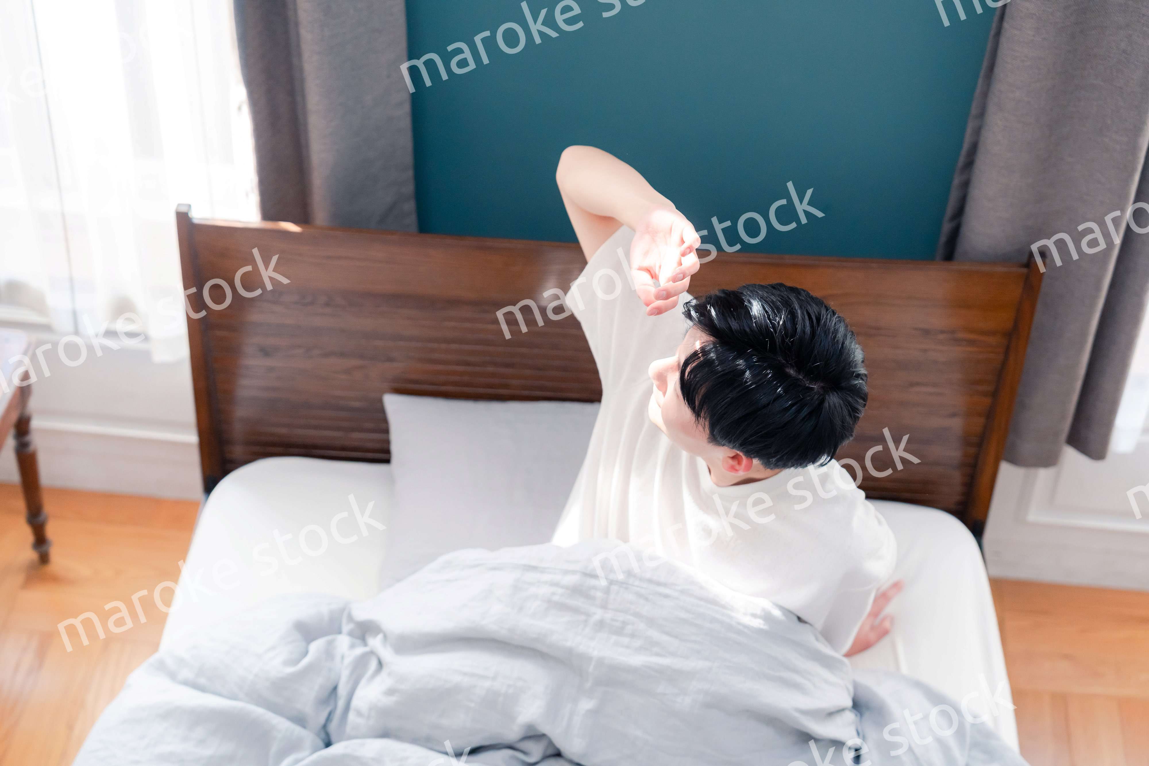 朝日が差し込む中で爽やかに目覚める若い男性