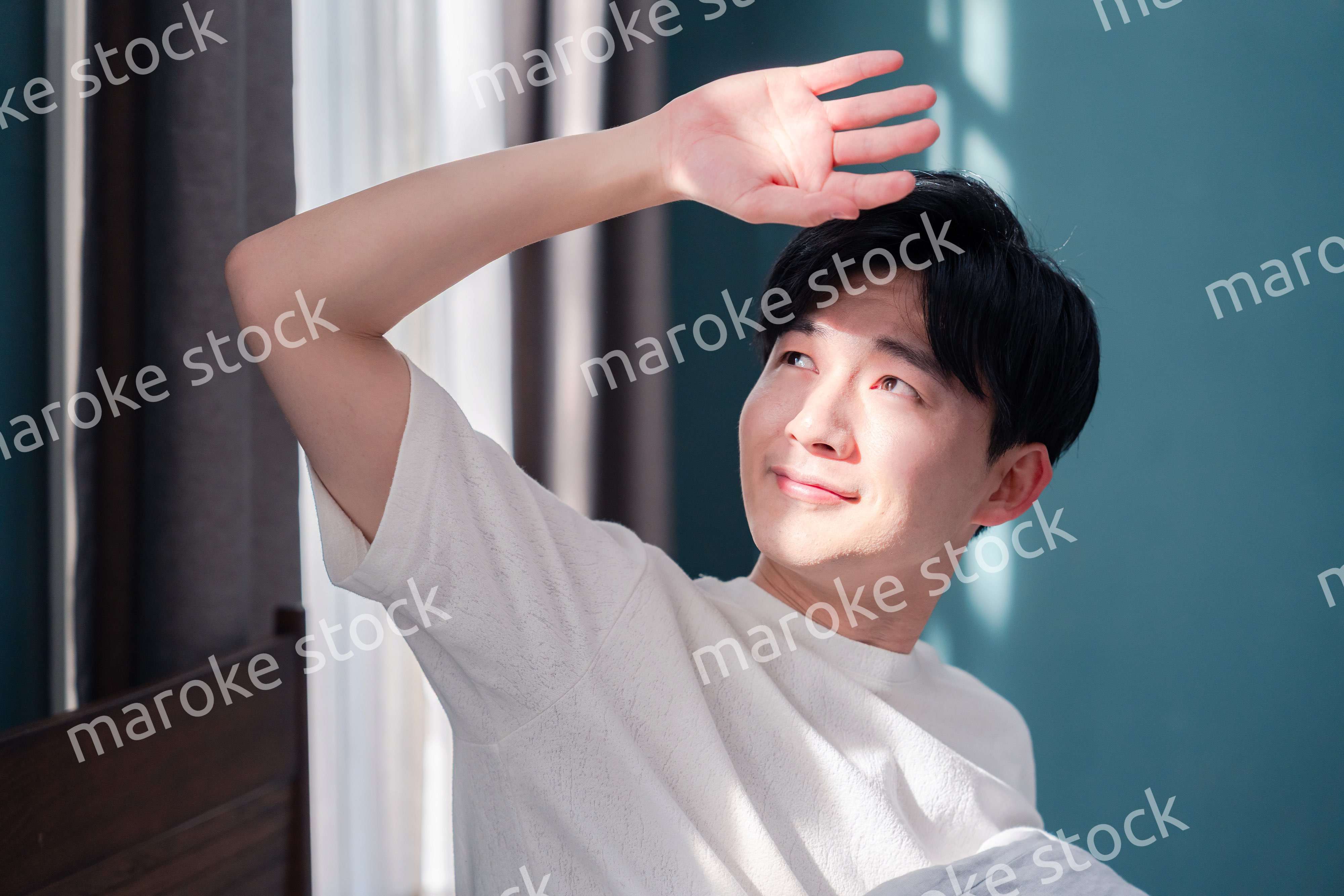 朝日が差し込む中で爽やかに目覚める若い男性