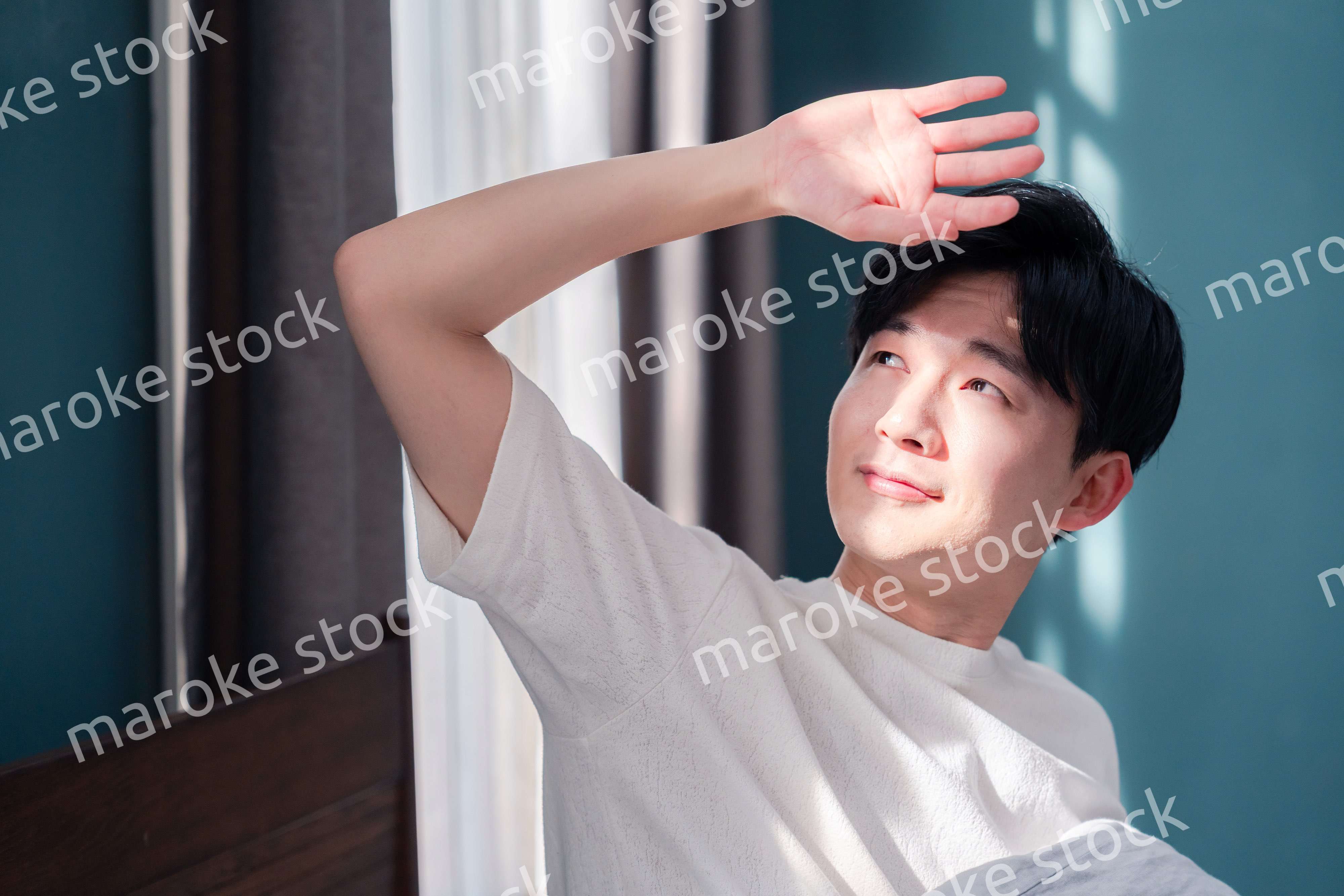 朝日が差し込む中で爽やかに目覚める若い男性