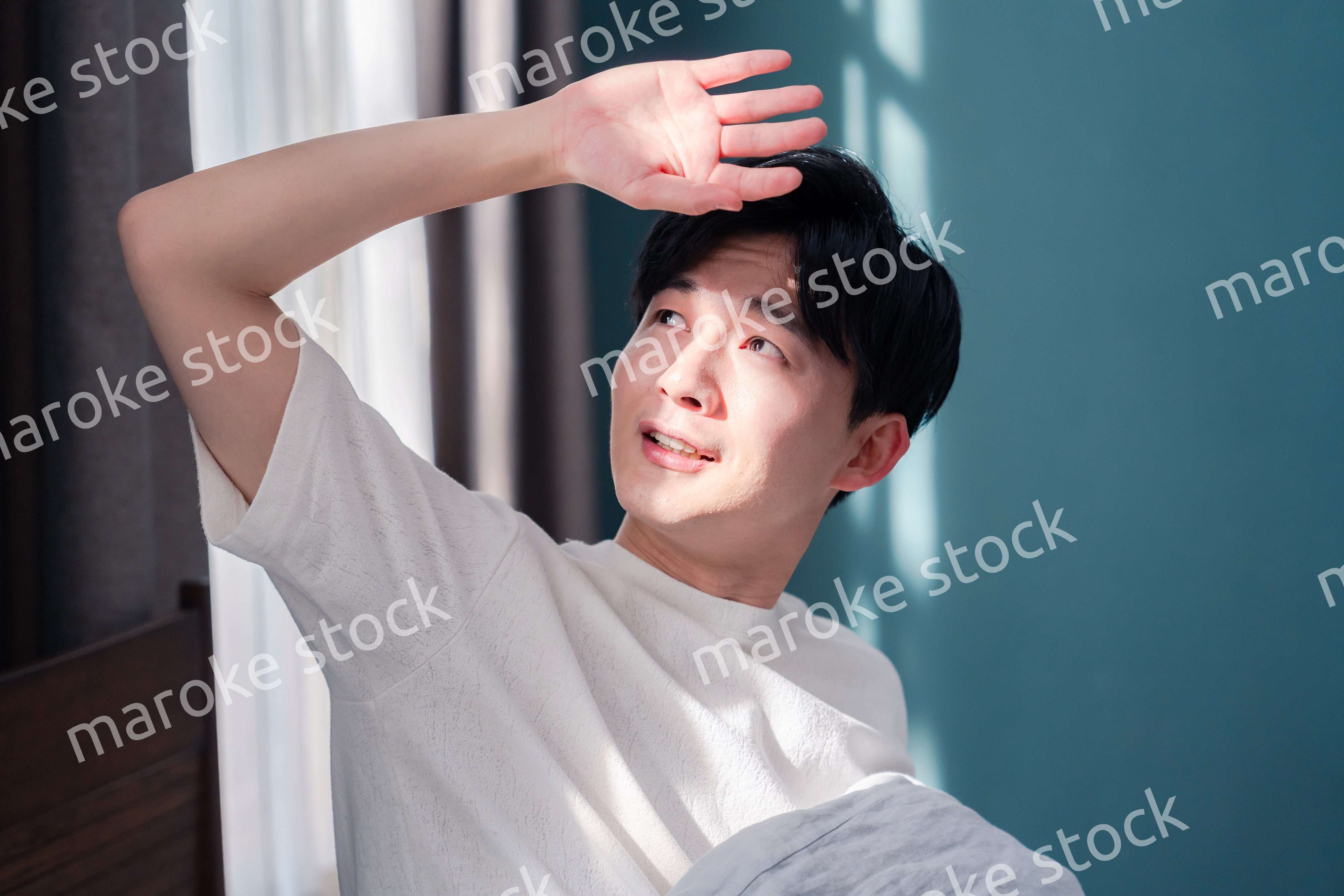 朝日が差し込む中で爽やかに目覚める若い男性