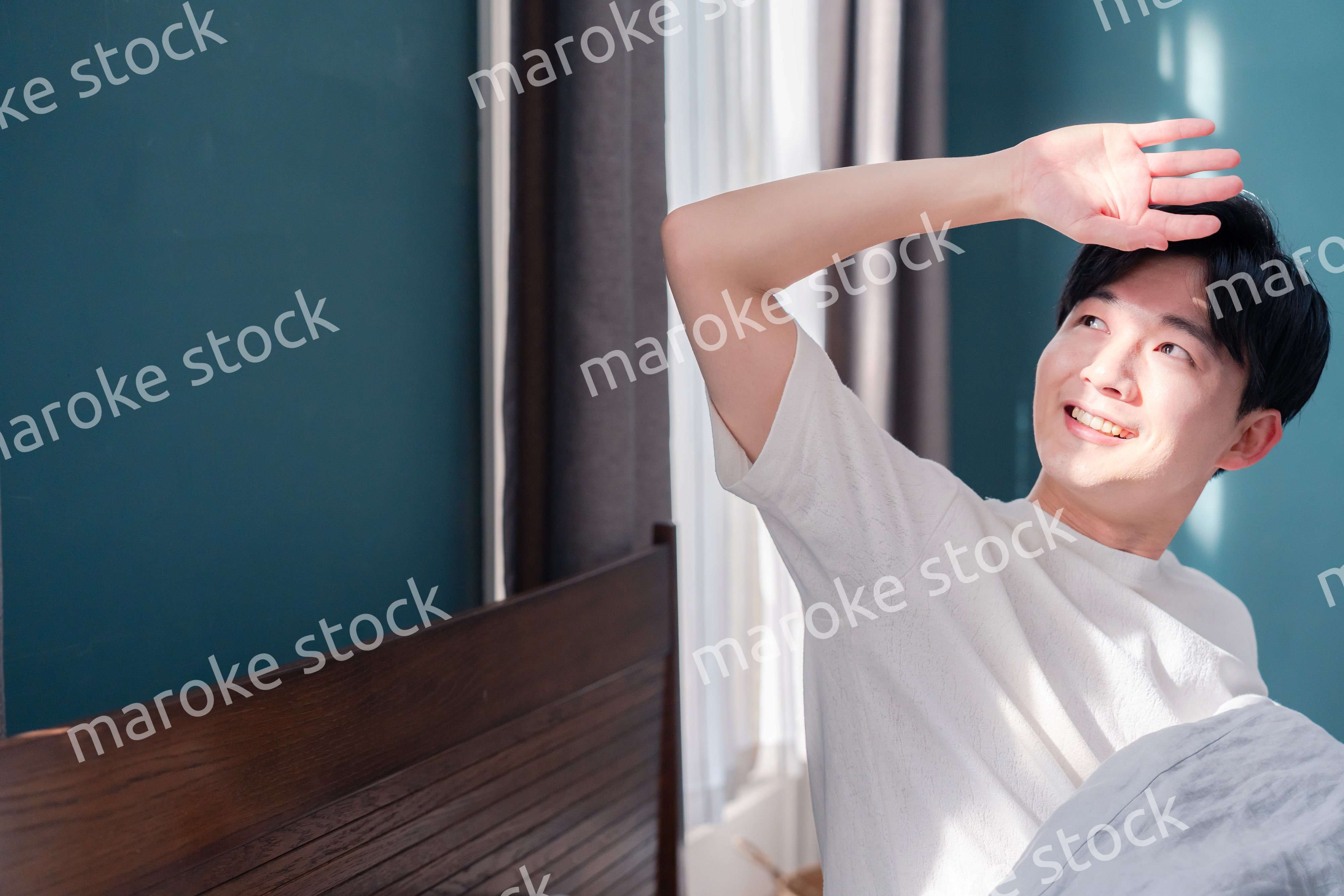 朝日が差し込む中で爽やかに目覚める若い男性