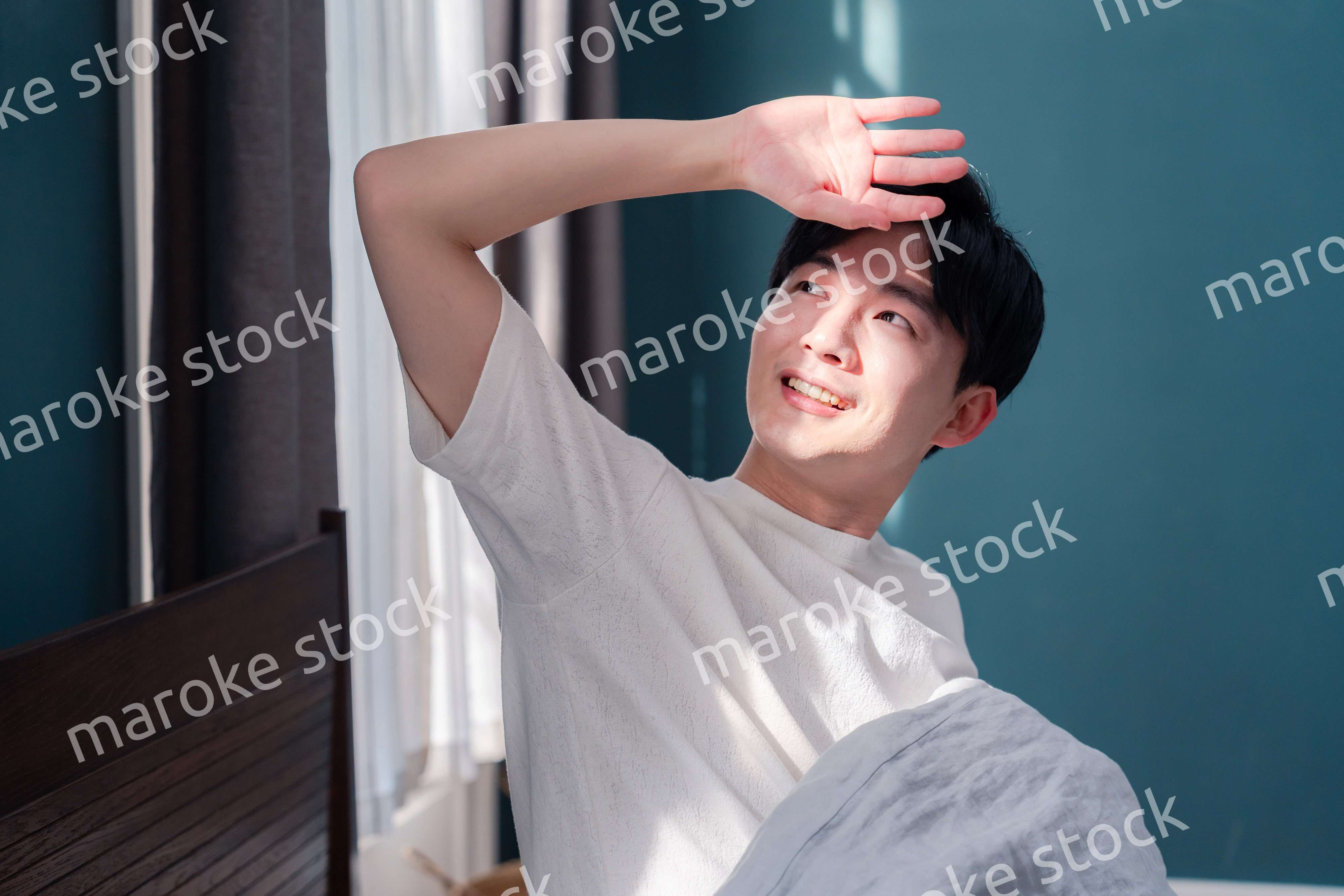 朝日が差し込む中で爽やかに目覚める若い男性