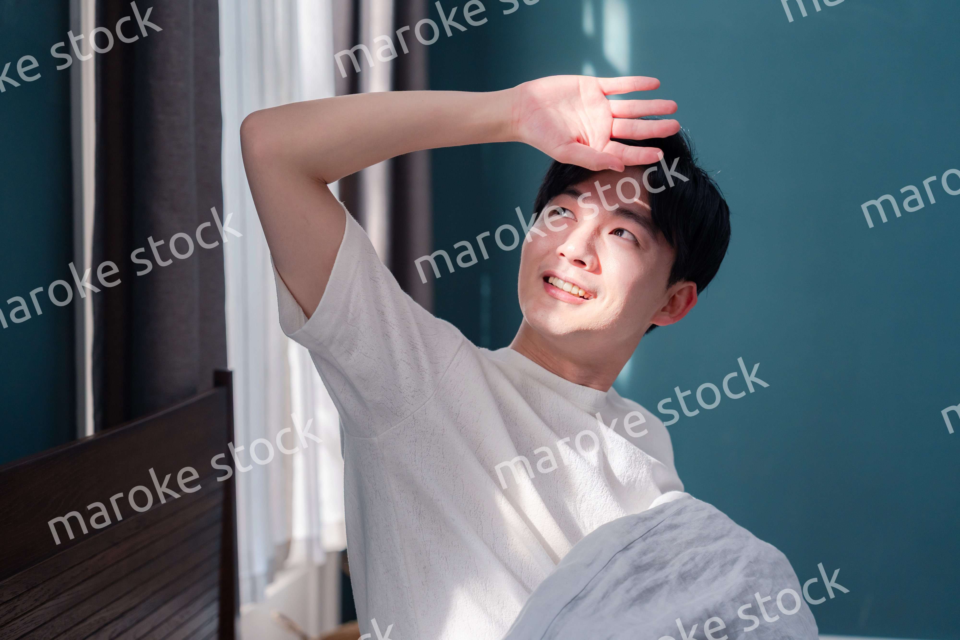 朝日が差し込む中で爽やかに目覚める若い男性