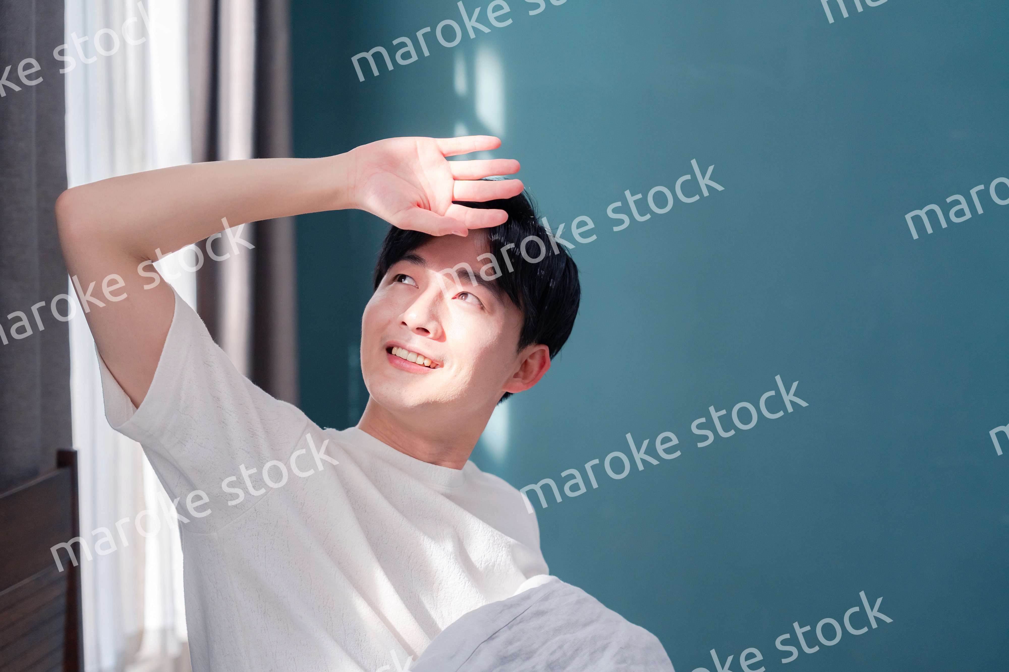 朝日が差し込む中で爽やかに目覚める若い男性