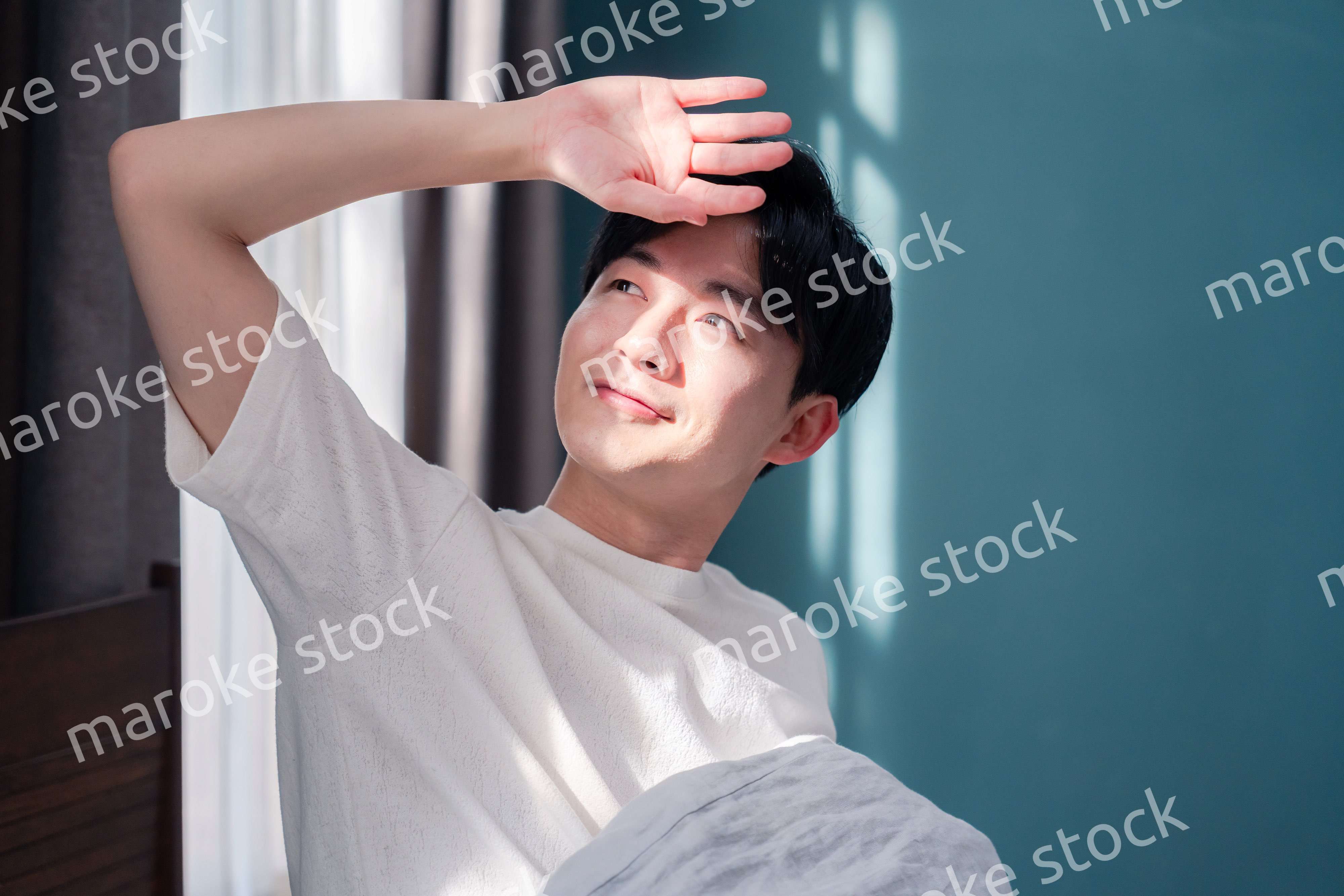 朝日が差し込む中で爽やかに目覚める若い男性