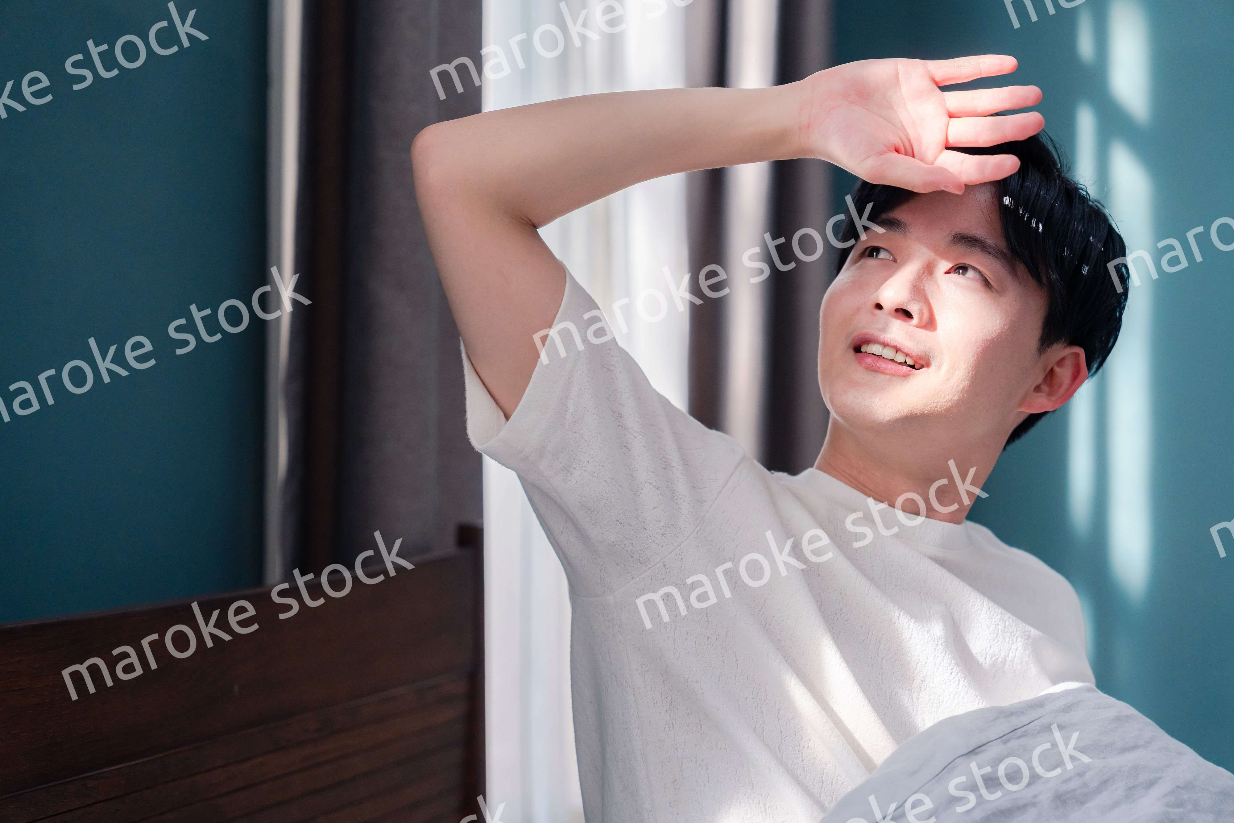 朝日が差し込む中で爽やかに目覚める若い男性