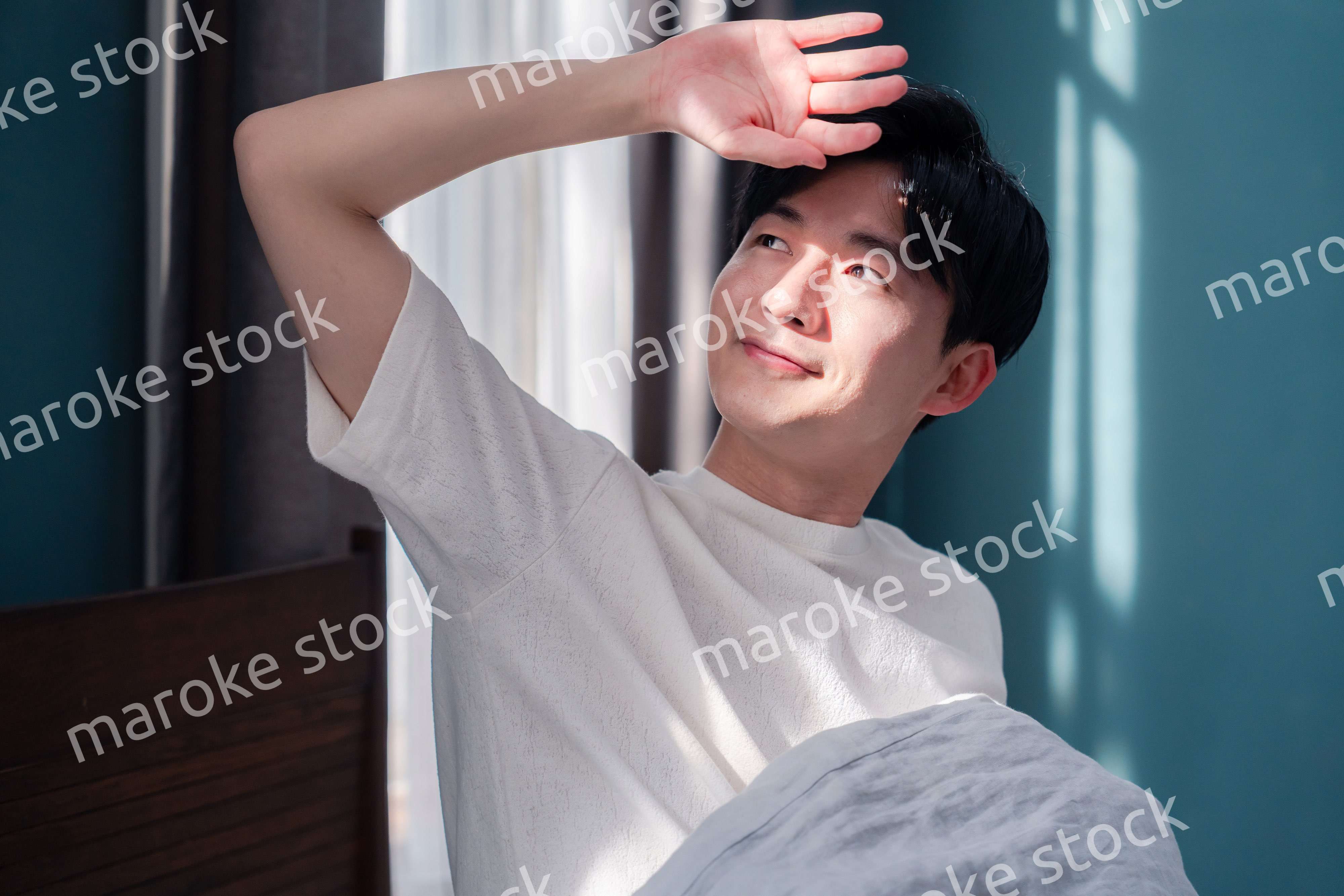 朝日が差し込む中で爽やかに目覚める若い男性