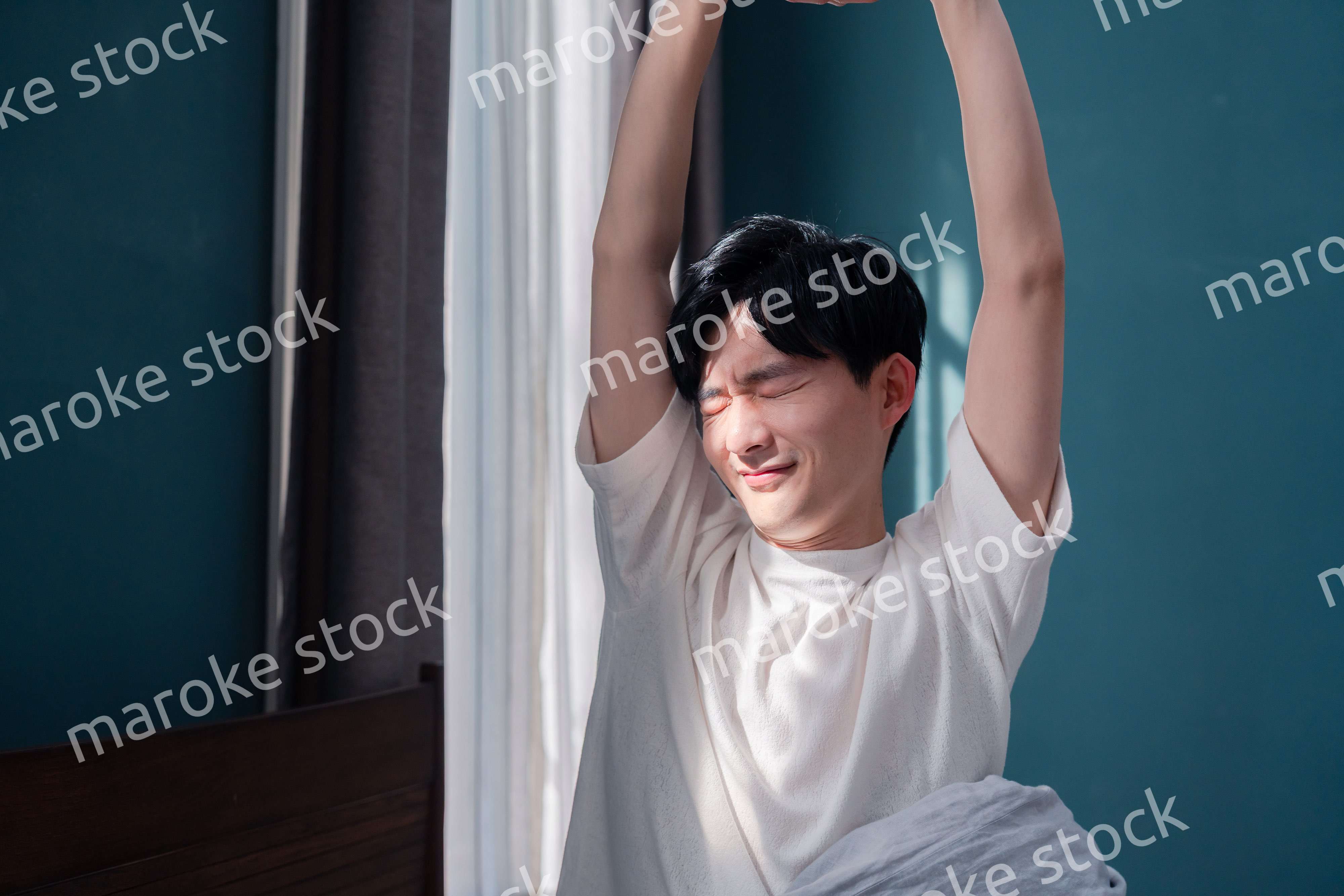 朝日が差し込む中で爽やかに目覚める若い男性