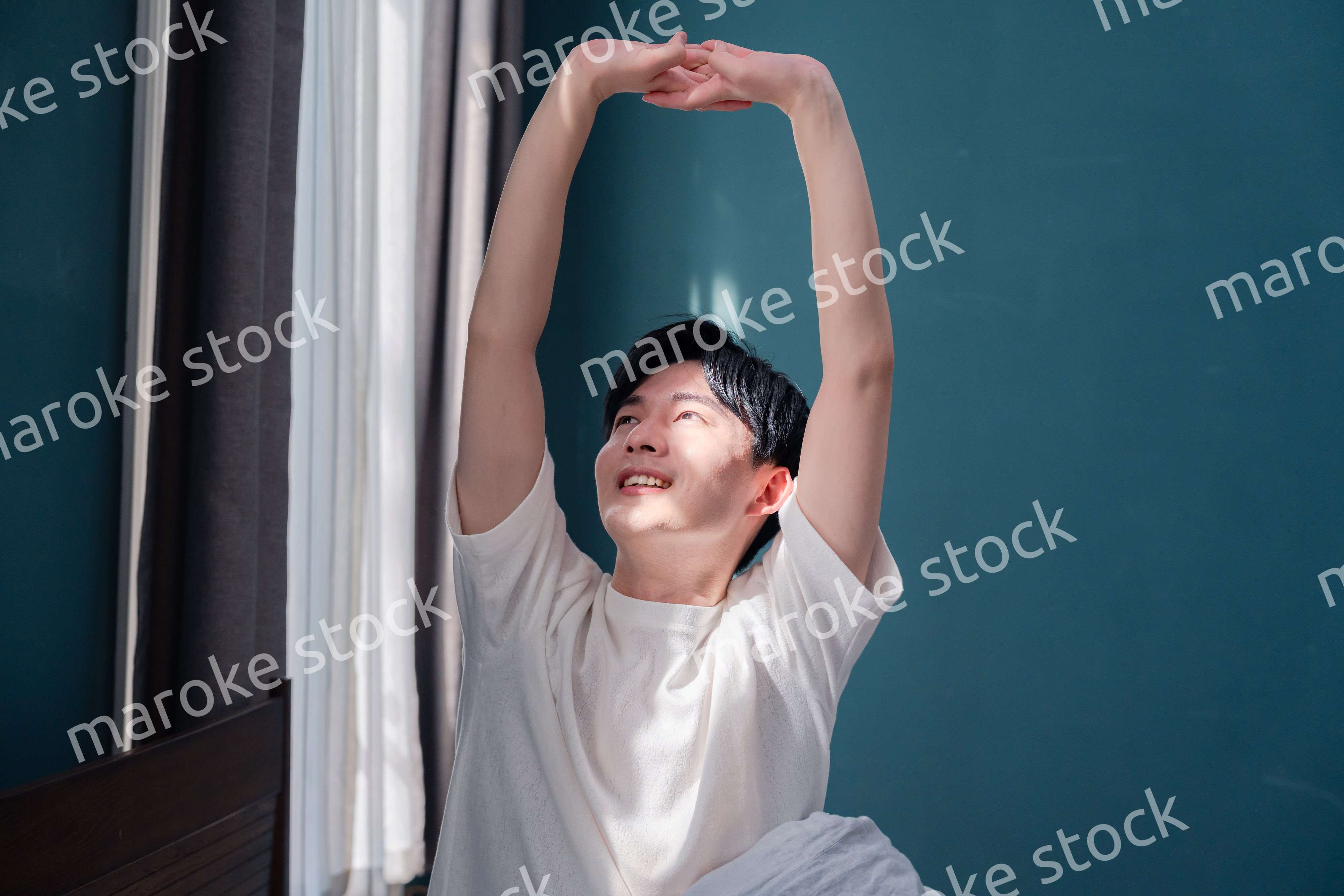 朝日が差し込む中で爽やかに目覚める若い男性