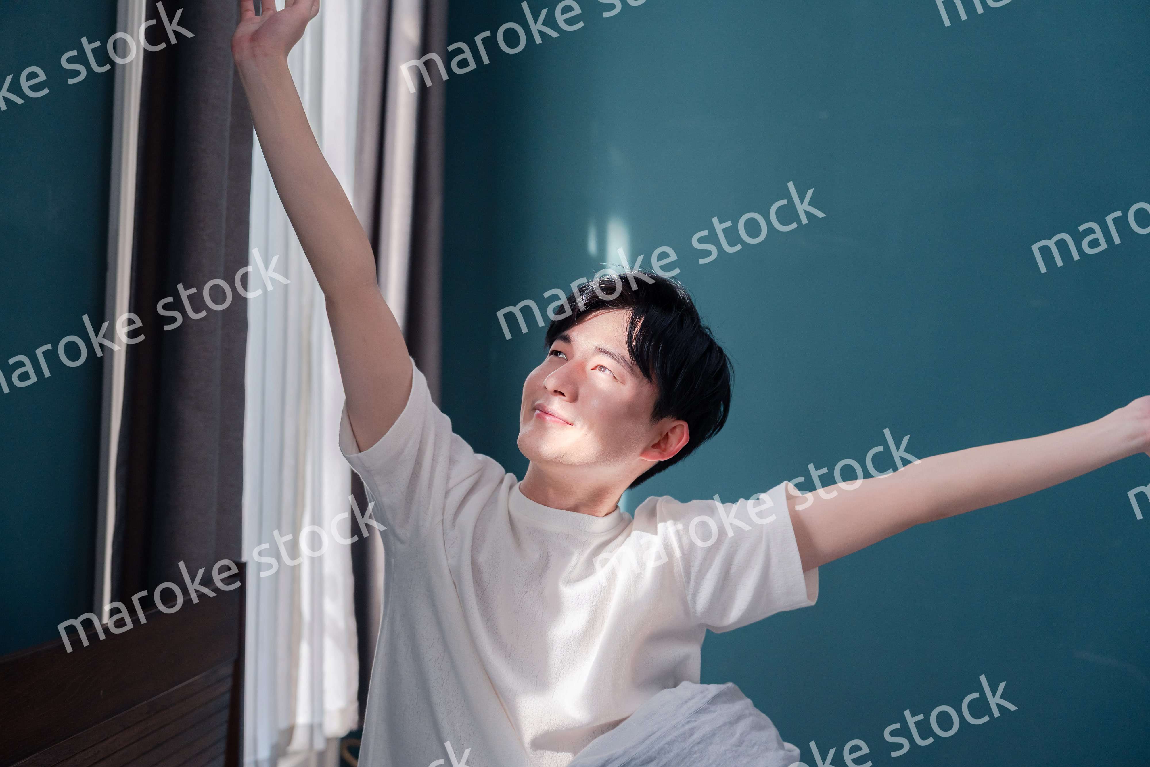 朝日が差し込む中で爽やかに目覚める若い男性