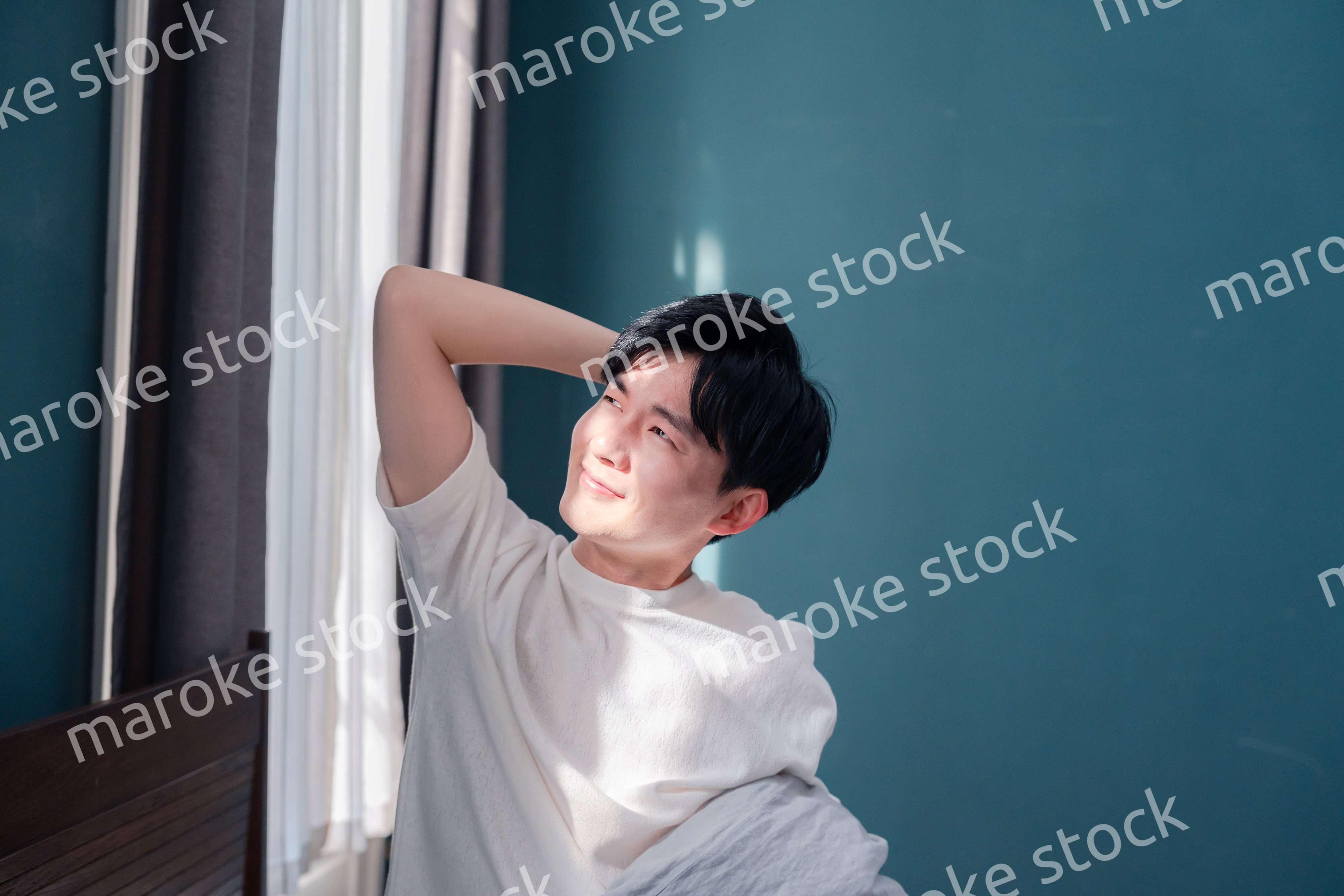 朝日が差し込む中で爽やかに目覚める若い男性