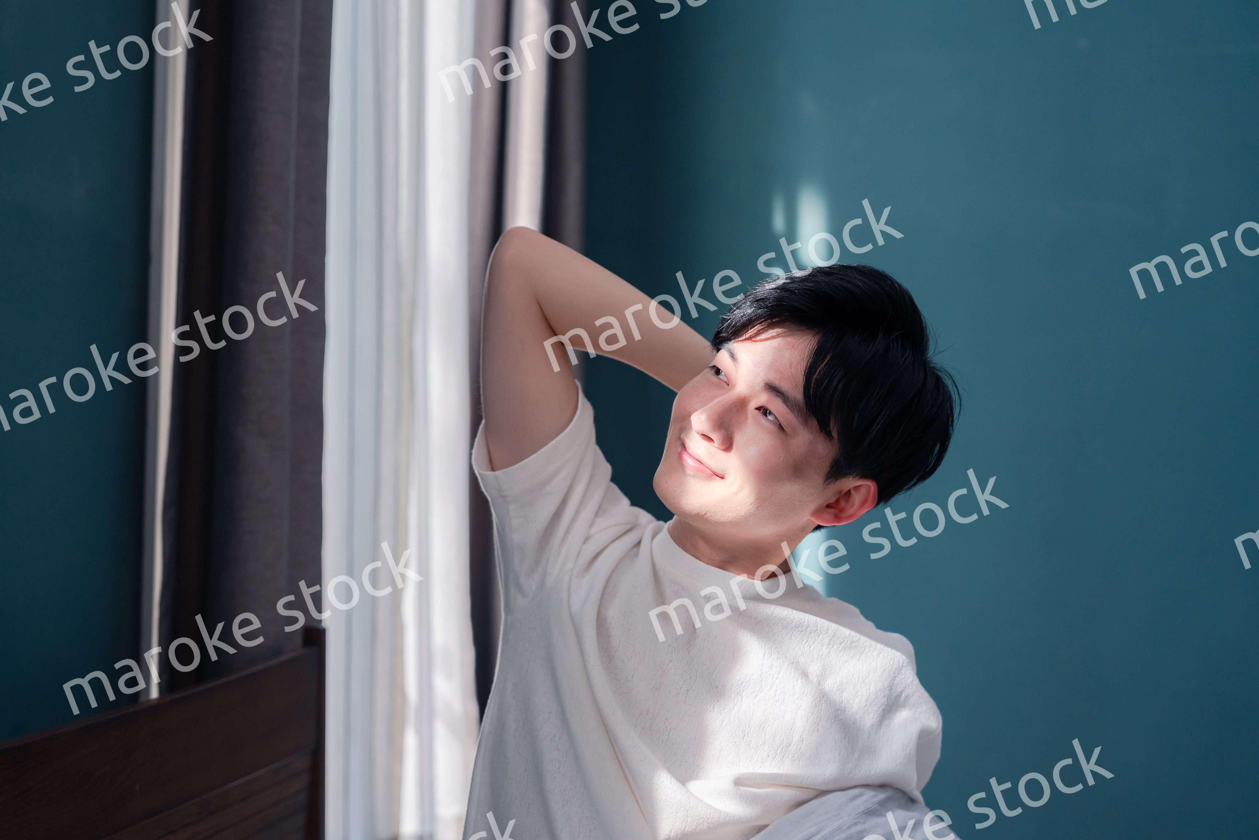 朝日が差し込む中で爽やかに目覚める若い男性