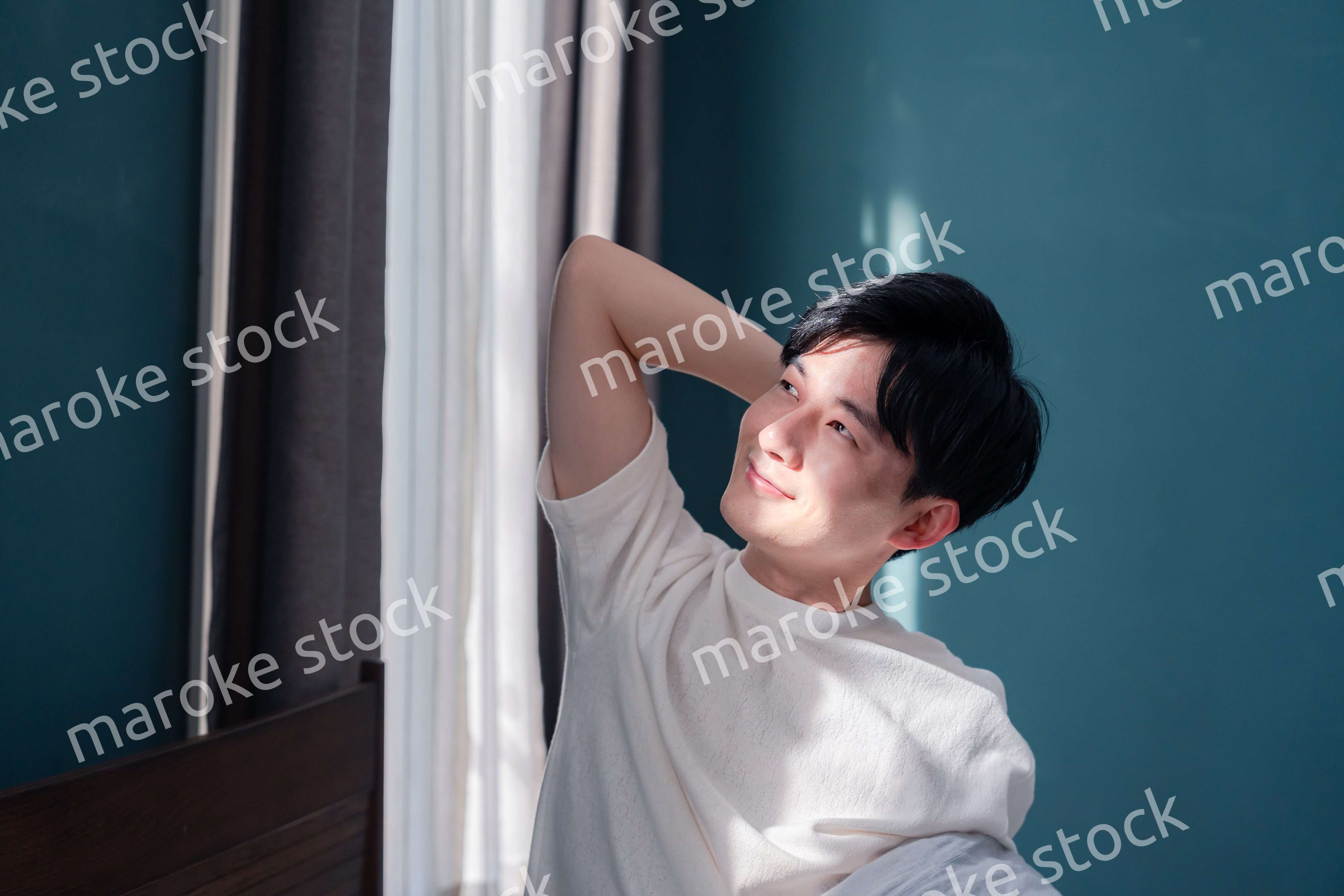 朝日が差し込む中で爽やかに目覚める若い男性