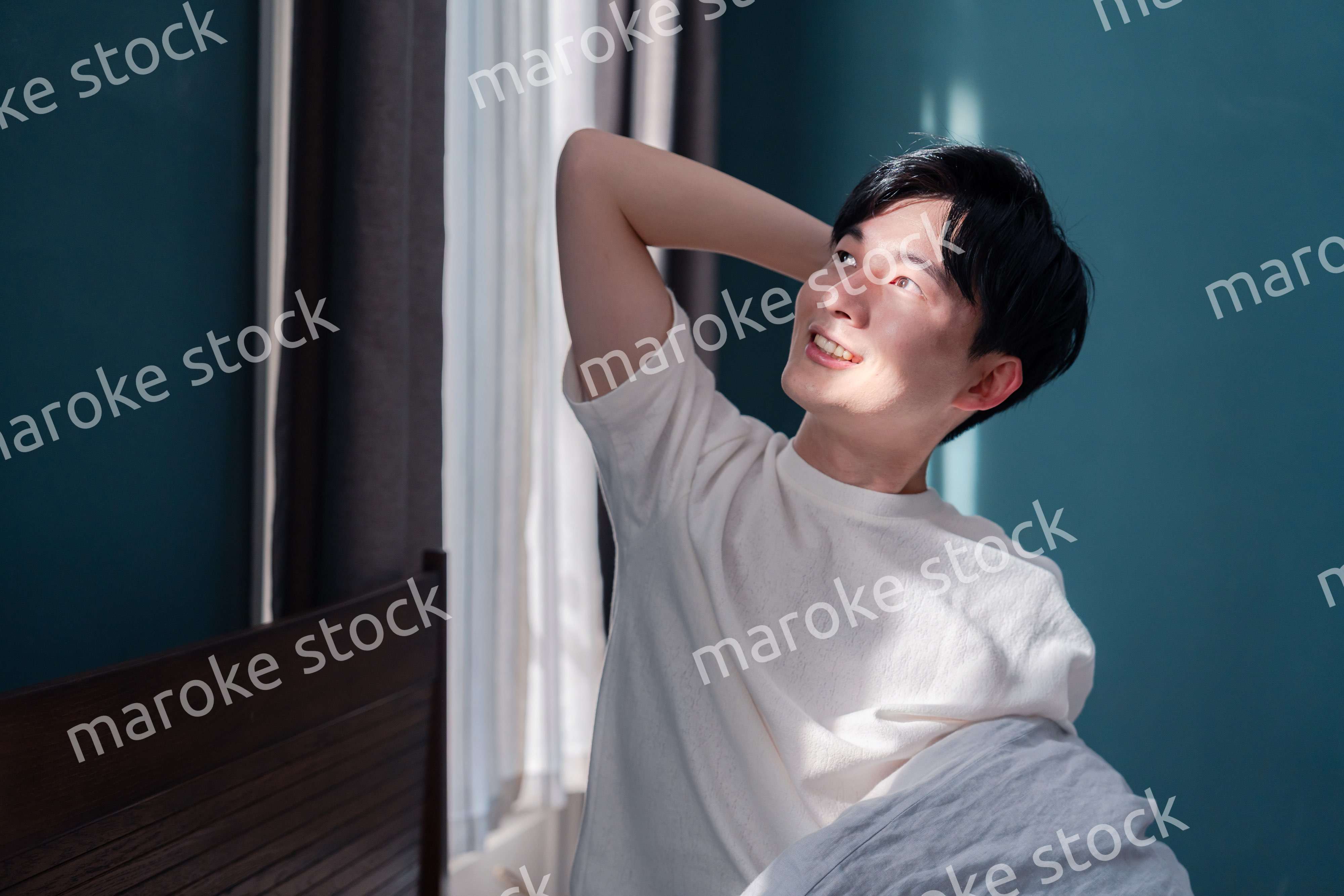 朝日が差し込む中で爽やかに目覚める若い男性