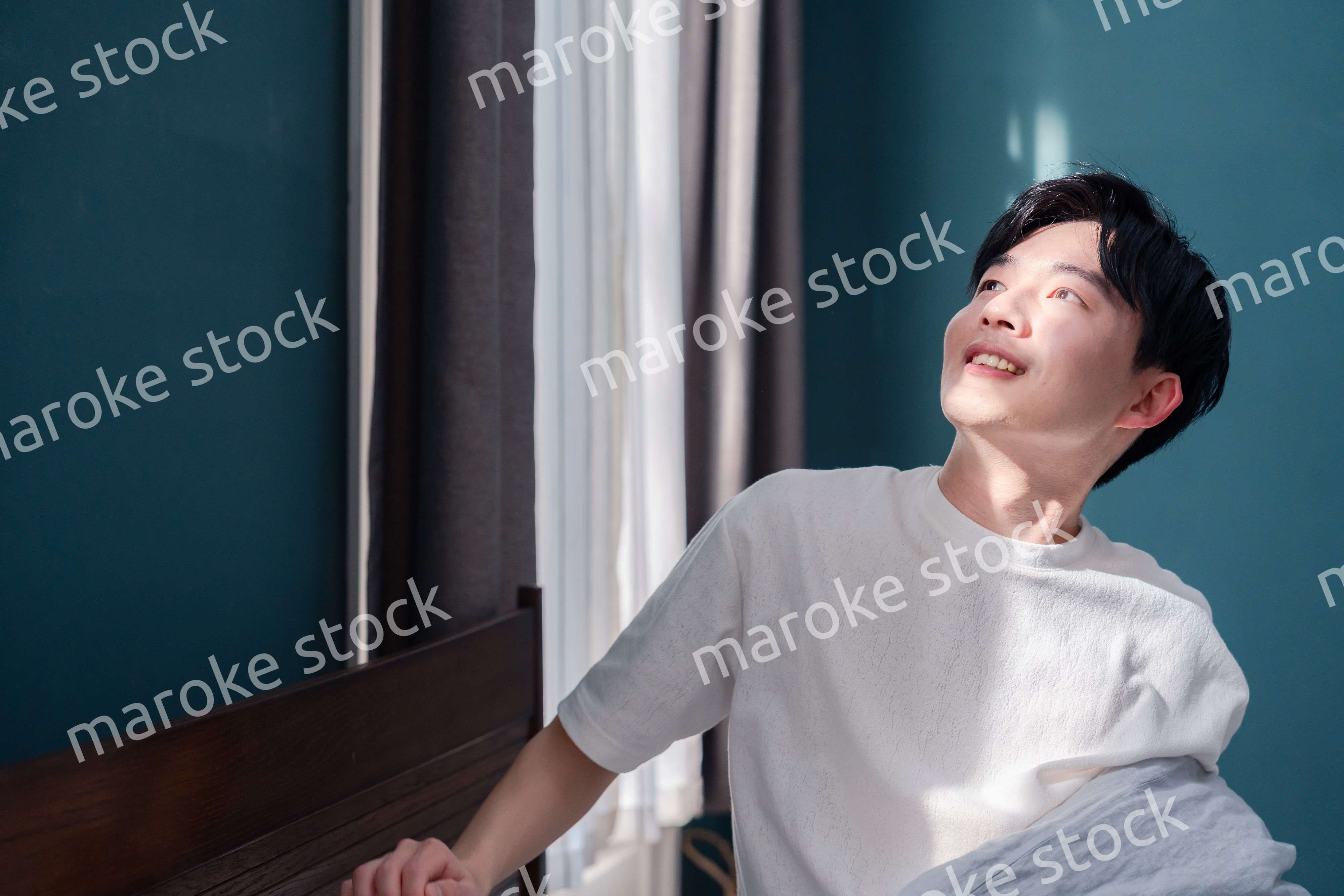 朝日が差し込む中で爽やかに目覚める若い男性