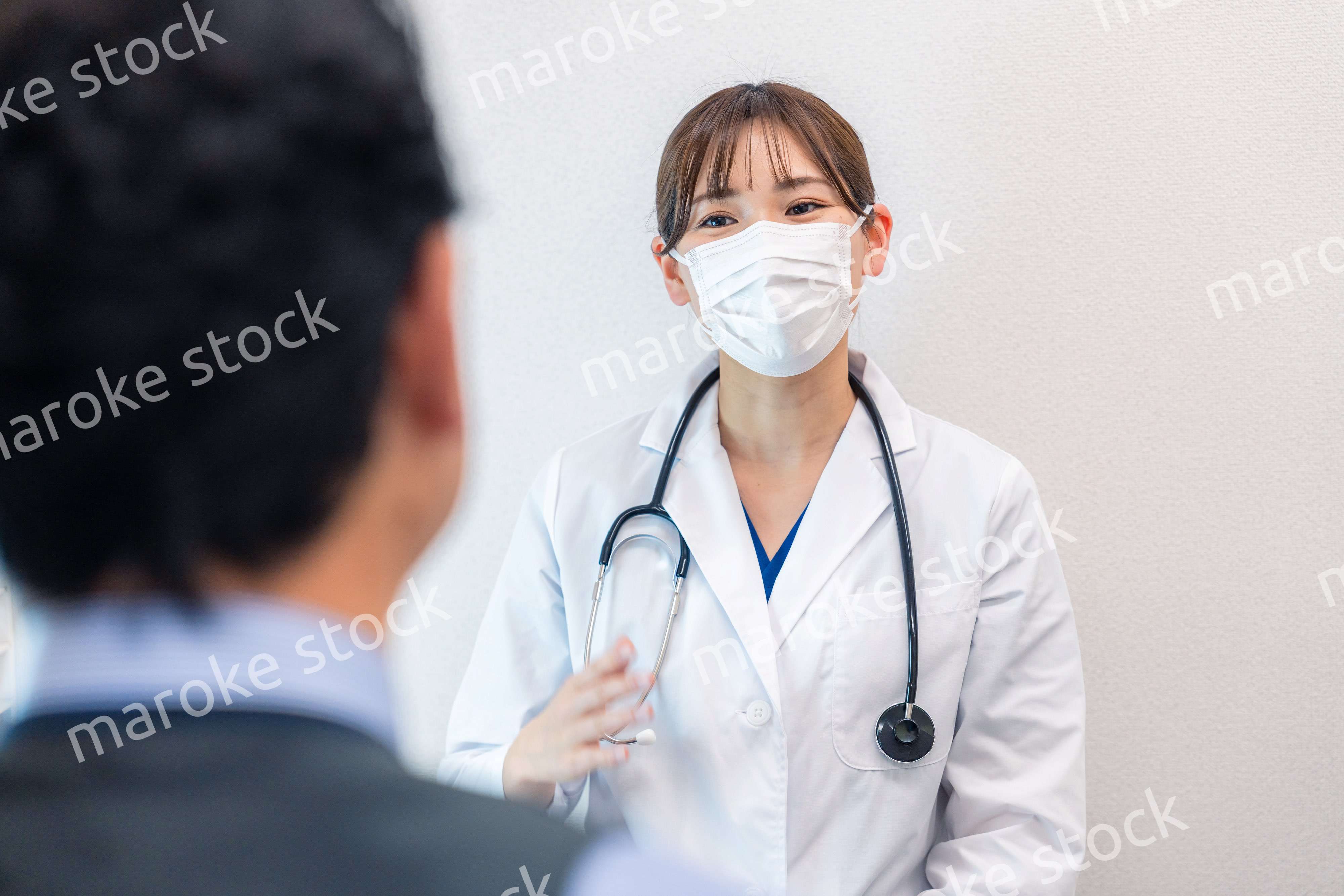 病院で男性患者の問診をする女性医師